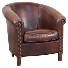 Fauteuil club en cuir de vache en bon état, avec des couleurs riches et profondes de style anglais