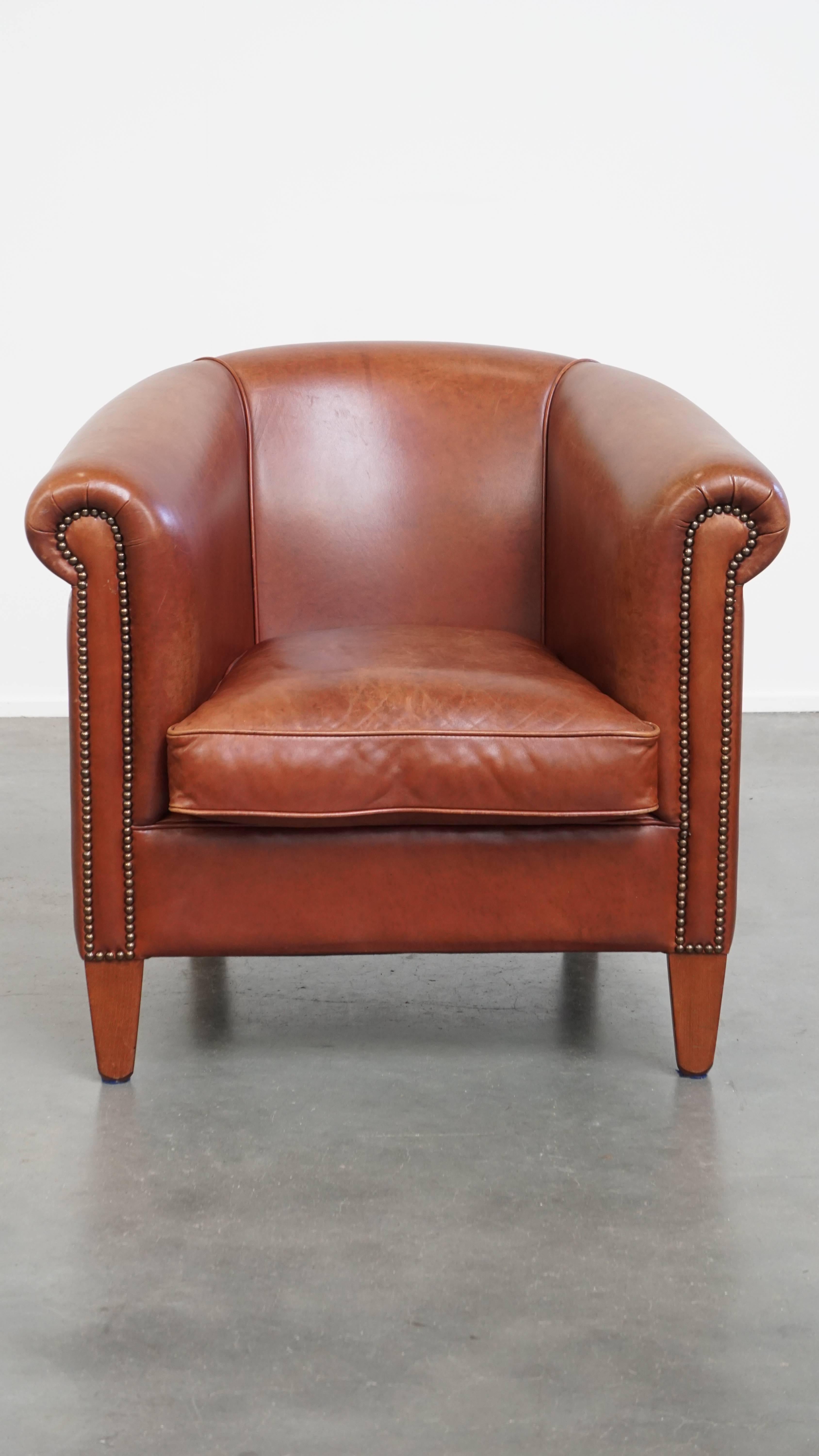 Offered here is this neat and well-maintained cowhide leather club armchair in a beautiful cognac color.

This stunning cognac-colored cowhide leather club chair, with its timeless design and comfortable seating, is the perfect spot to relax after a