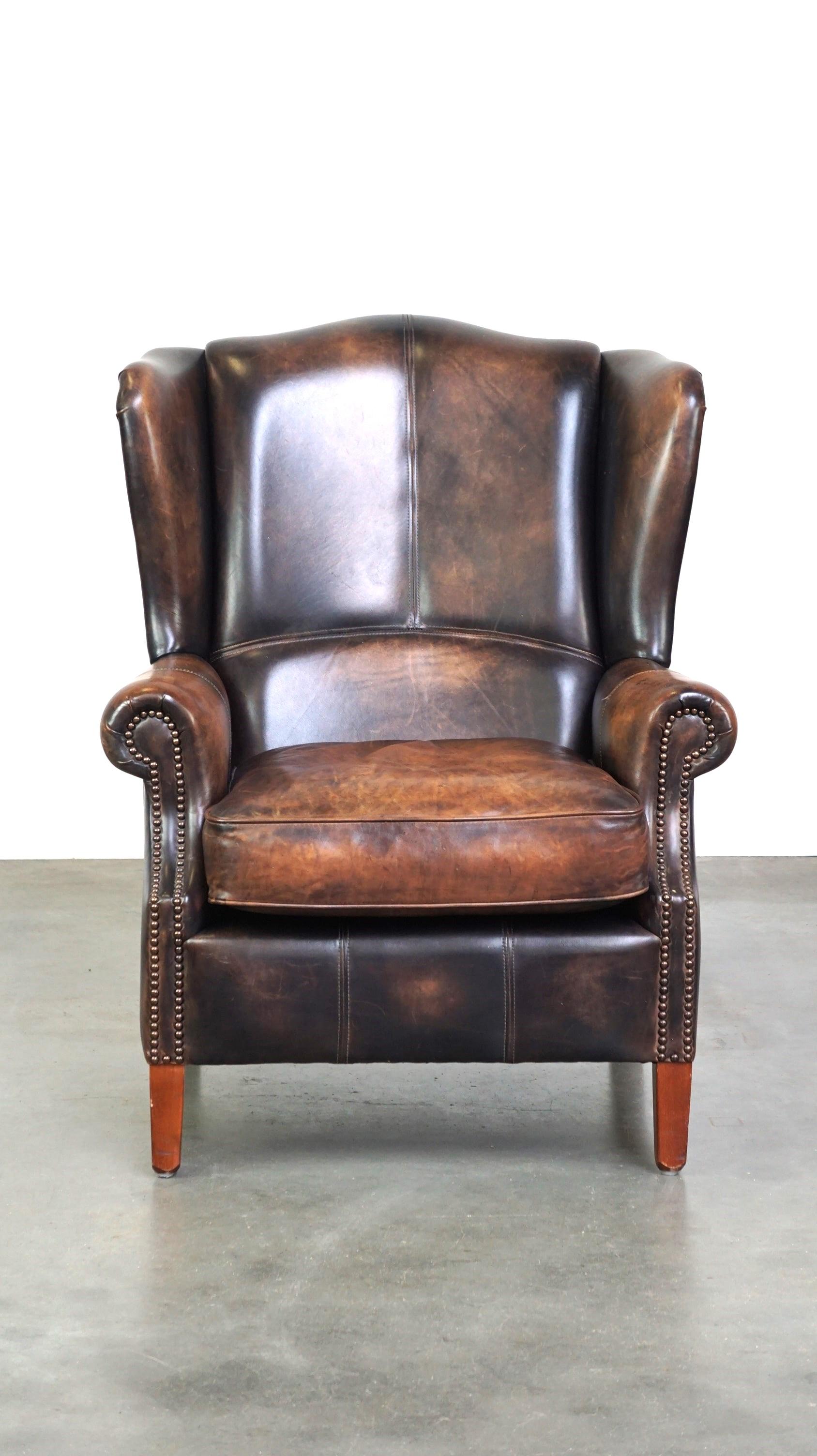This charming cowhide leather wingback armchair features a distinctive color combination, giving it a unique appearance. No interior is complete without a comfortable armchair like this one to relax in after a long day. It has a sleek finish and