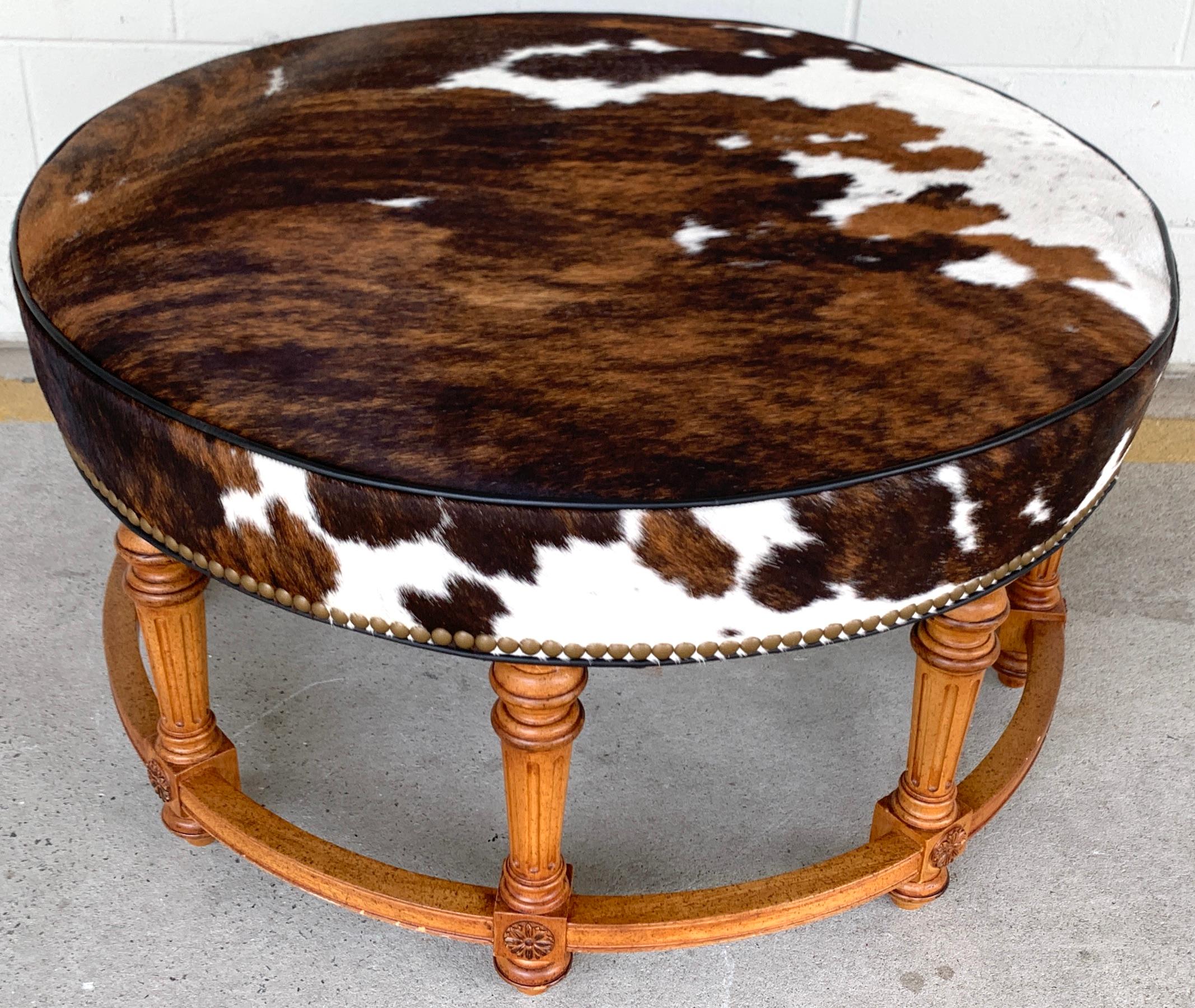 Cowhide ottoman by Hancock and Moore, exceptional cowhide, with leather binding raised on six fluted legs joined by a circular stretcher.
   