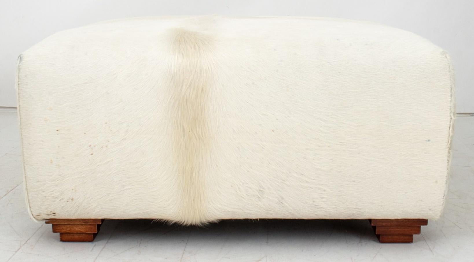 Cowhide Upholstered Storage Pouf or Ottoman fully upholstered in hide above ziggurat stacked feet, the hinged pouf opening to reveal storage.

Dimensions:   18