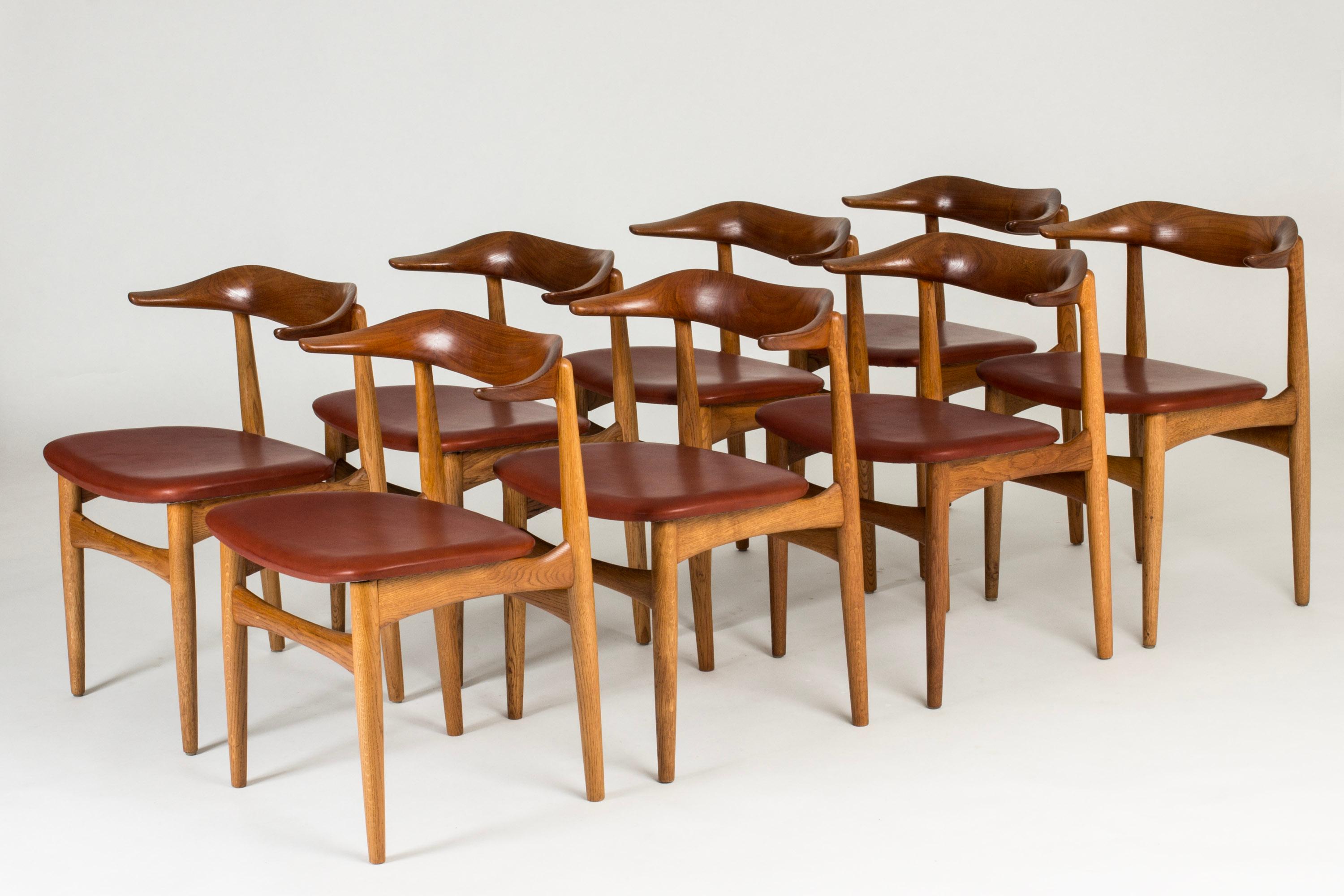 Set of eight “Cowhorn” dining chairs by Knud Færch, made from teak with dark cognac leather seats. Beautifully sculpted backrests in a distinct, undulating form.