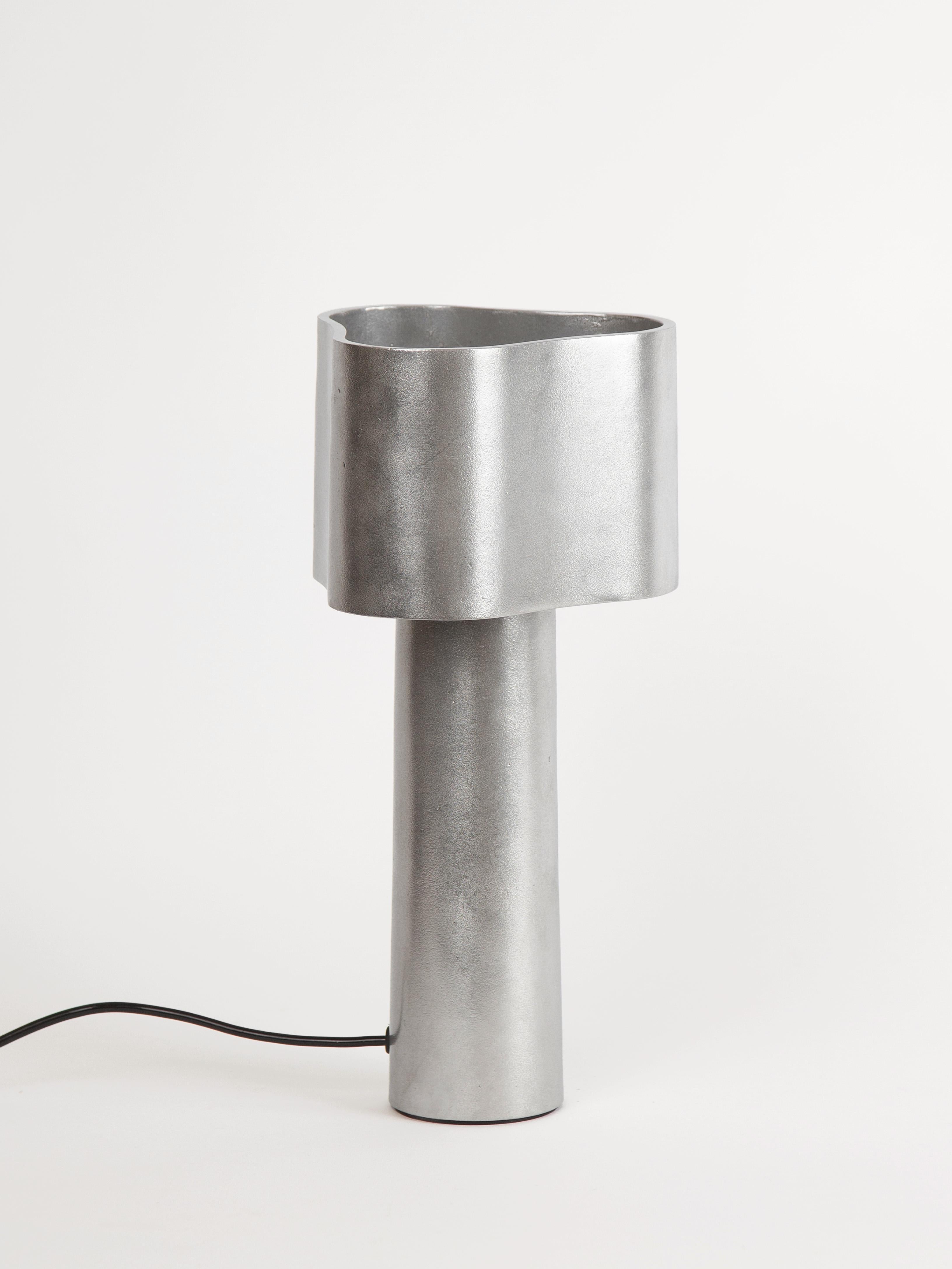 Coy Table Lamp by Stem Design
Dimensions: Ø 19 x H 36 cm. Body Height: 24 cm.
Materials: Cast aluminum.
Finish: Tumbled and burnished. 
Weight: 3 kg.

Finished and assembled by hand in India.

Coy embraces singularity in design, exploring the