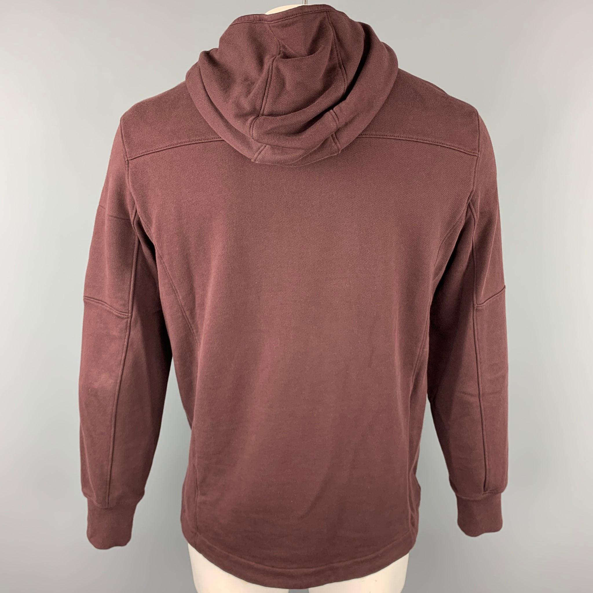 CP COMPANY jacket comes in a dark burgundy cotton featuring a hooded style zipper details, lens detail, high collar, and a zip up closure. 

Good Pre-Owned Condition.
Marked: XL

Measurements:

Shoulder: 19.5 in. 
Chest: 44 in. 
Sleeve: 26.5 in.