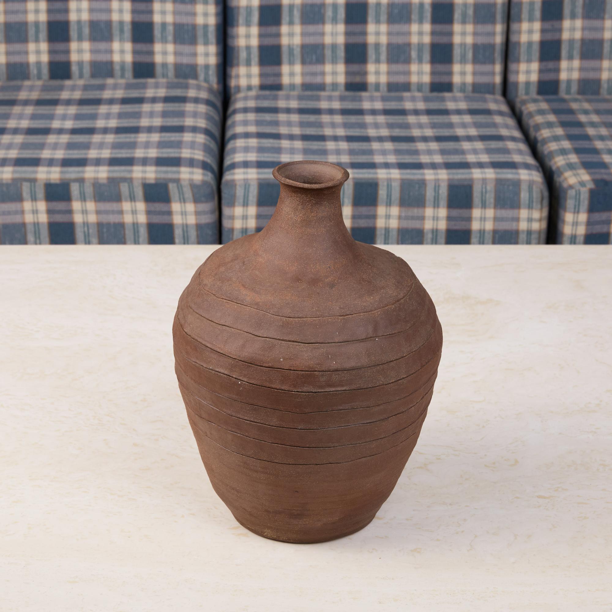 Reminiscent of a Primitive jug, this unglazed dark brown ceramic vessel is quite large and has eight undulating lines cut into its center. Unlike so many contemporary ceramics, while this piece was thrown on a wheel it also has texture from fingers
