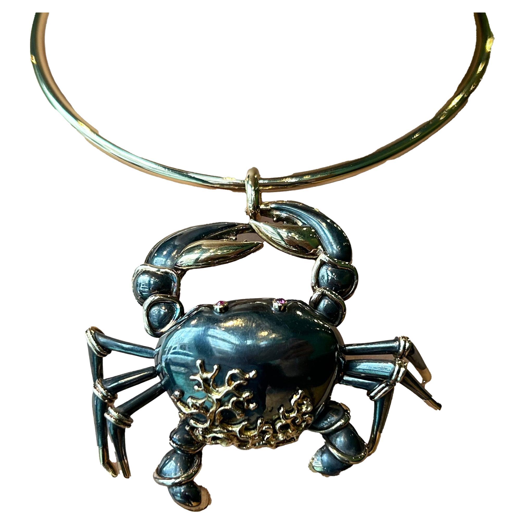Anhänger in Form eines Kastens aus oxidiertem Silber (800‰) und Gold (750‰), stilisiert als Krabbe, mit Augen aus Rubincabochons und beweglichen Beinen. Unterzeichnet René BOIVIN. Sie ist mit einer schwarzen Kordel verziert und hat einen goldenen