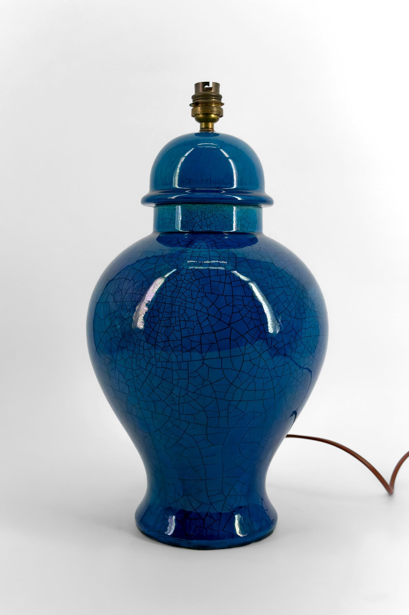 Nous vous présentons cette splendide lampe en céramique émaillée bleue craquelée, fabriquée en France dans les années 1950. 

Ce modèle, bien que non signé, rappelle les œuvres emblématiques du maître céramiste Pol Chambost, tant par la forme que