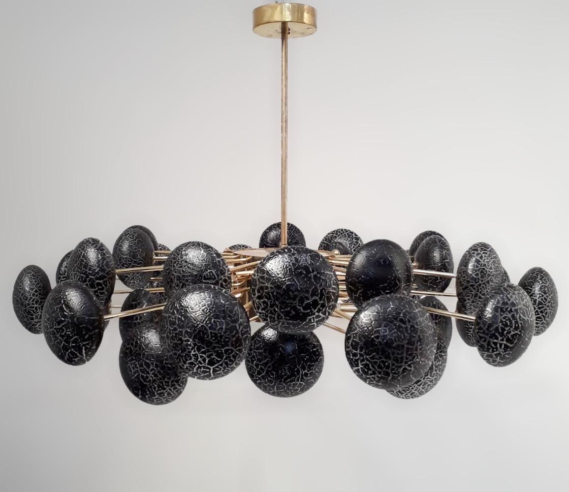 Limited edition Italian chandelier with crackled black Murano glass orbs, mounted on newly made polished brass frame / Designed by Fabio Bergomi for Fabio Ltd / Made in Italy
12 lights / G9 type / max 40W each
Measures: Diameter 49 inches / height