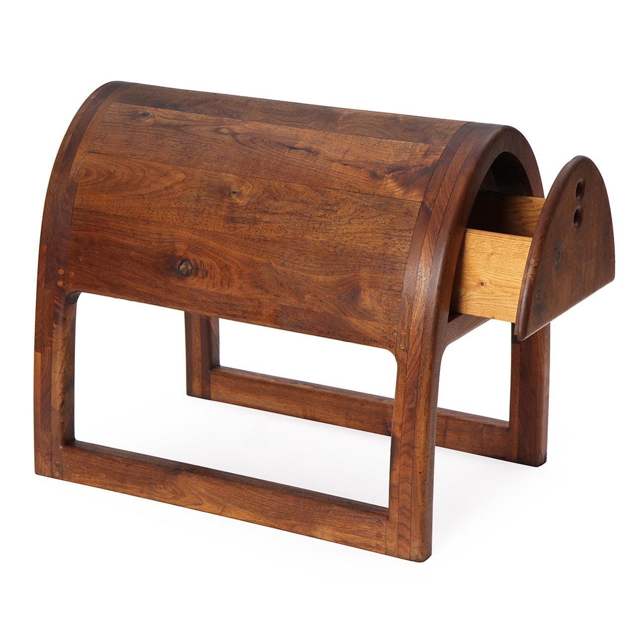 A unique California craft-movement artist-built saddle stand and cabinet made of warmly figured staved planks of walnut having a drawer on each side with recessed finger pulls, the structure floating above full length sled-legged base.