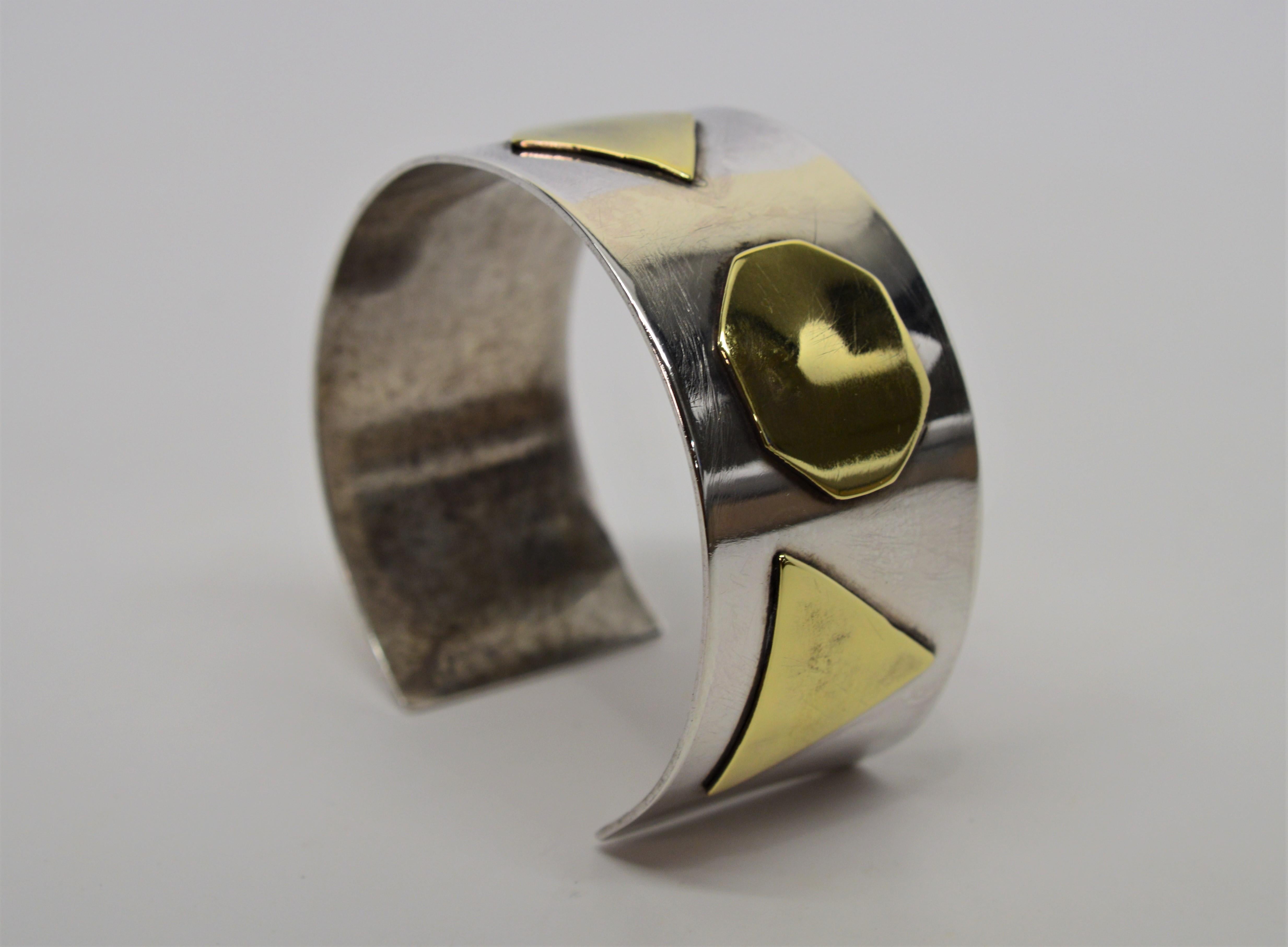 A fabulous artisan style piece, this cuff bracelet is made of .925 Sterling Silver and has contrasting Brass geometric appliques that bestows character and style. The mix metals cuff measures 2-1/4 inch by 2 inches and has an inside circumference of