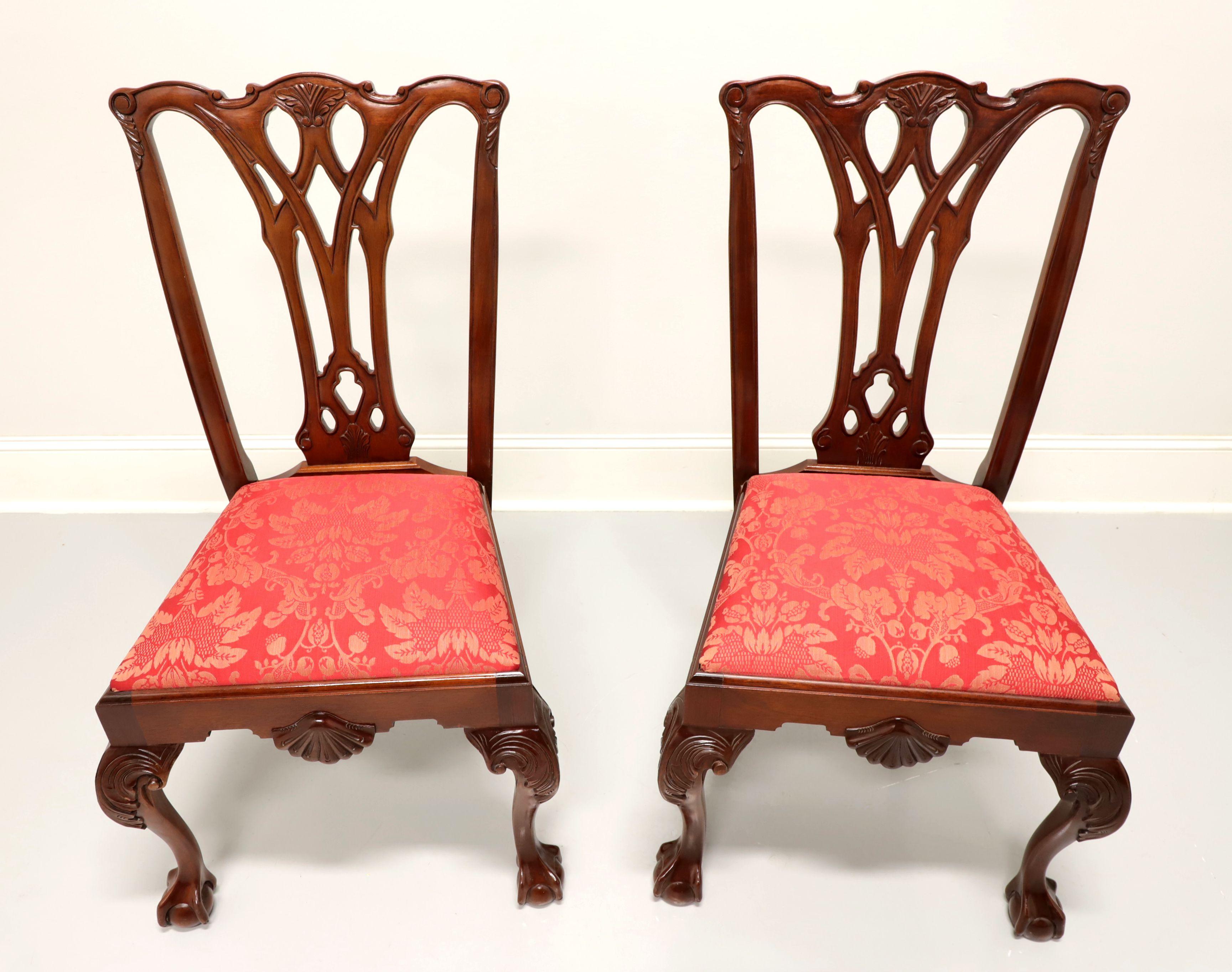 A pair of Chippendale style dining side chairs by Craftique. Solid mahogany with carved crest rail, carved back, red & gold colored brocade like fabric upholstered seat, carved shell to front apron, carved acanthus leaf to knees, curved legs and