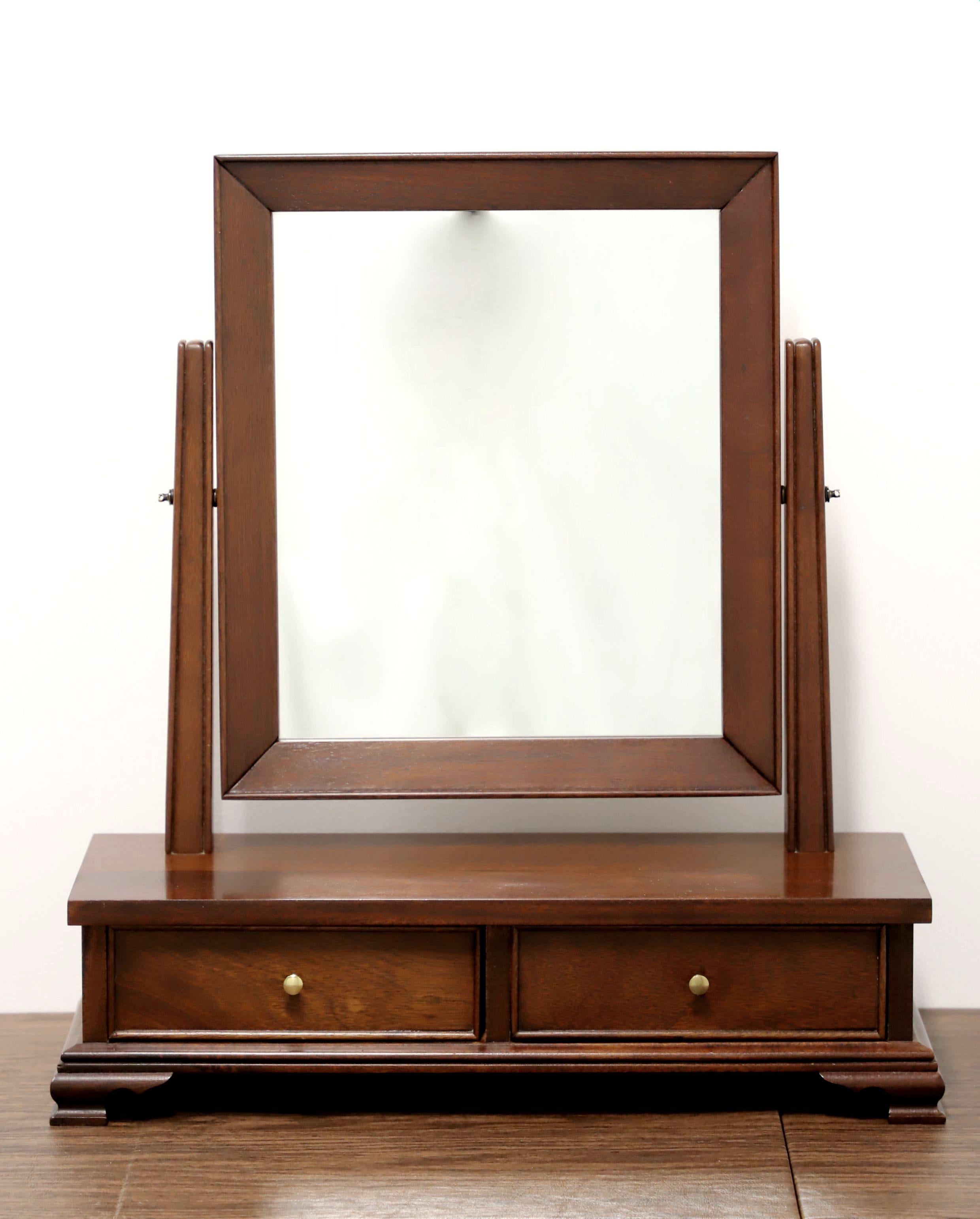 A Chippendale style cheval dressing table mirror by high-quality furniture maker Craftique. Mirrored glass, portrait oriented, mahogany frame with their Mellowax finish, attached by decorative brass pivot screws to post-like sides, a two-drawer