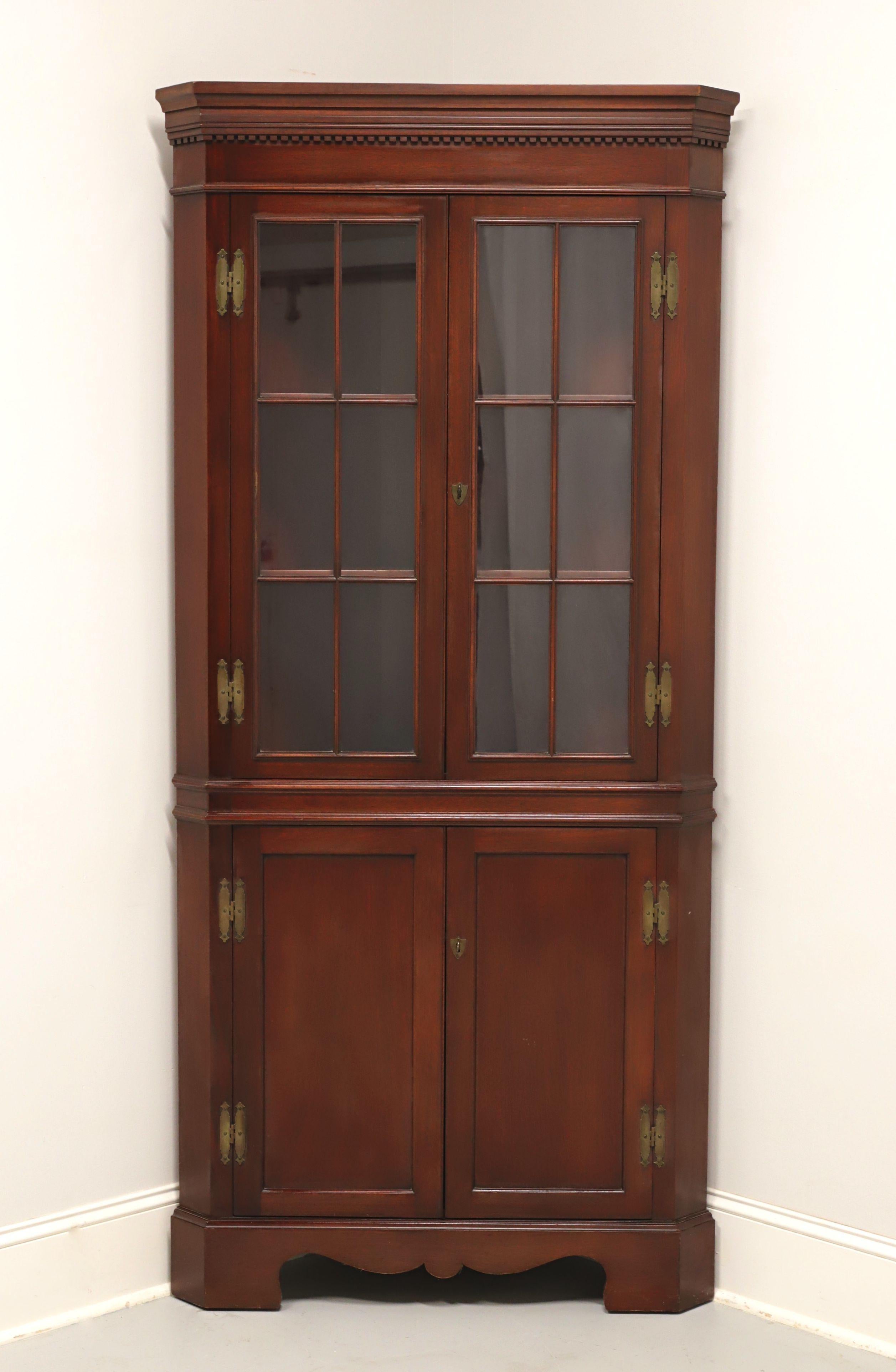 A Chippendale style corner cupboard by high-quality furniture maker Craftique. Solid mahogany, likely with their Colonial finish, crown & dentil molding to top, carved apron, and bracket feet. Upper cabinet features two fixed plate-grooved wooden