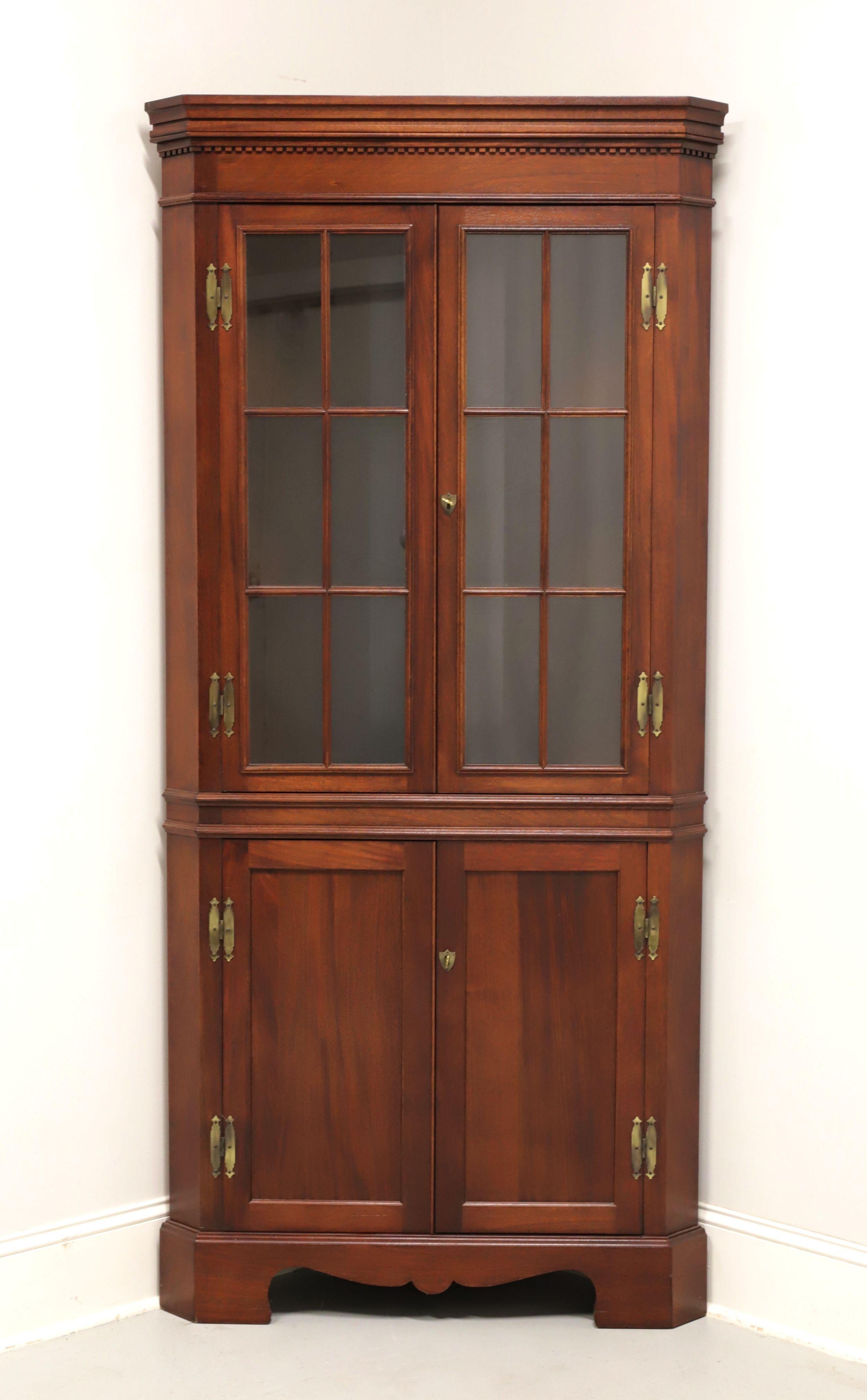 A Chippendale style corner cupboard by high-quality furniture maker Craftique. Solid mahogany with their Old Wood finish, crown & dentil molding to top, carved apron, and bracket feet. Upper cabinet features two fixed plate-grooved wooden shelves