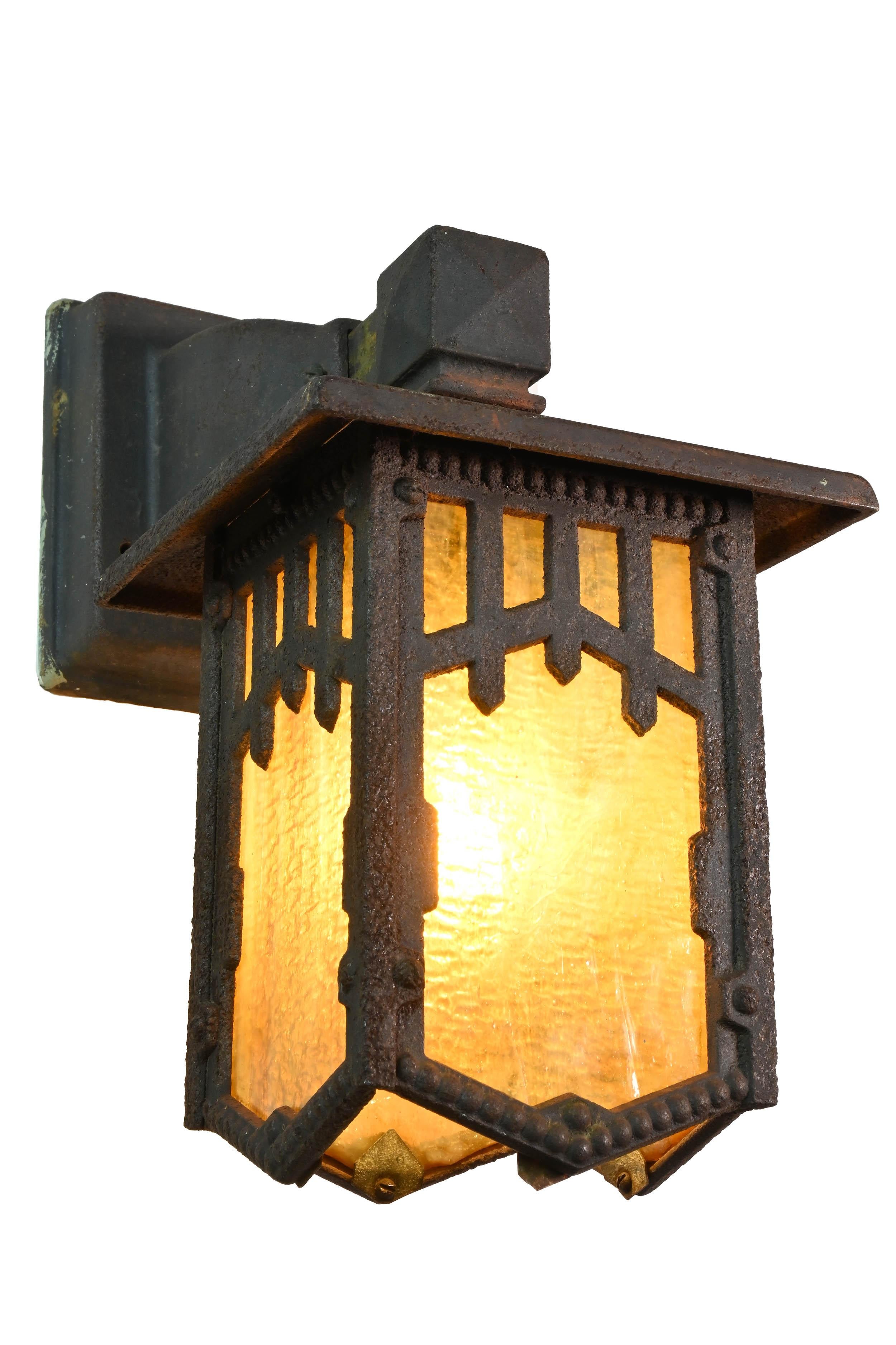 Cast iron sconce pair with original patina finish and original iridescent caramel slag glass. Simple sconce design Arts & Crafts decorative ornamentation. This sconce pair lighting fixtures Perfect for a front porch or inside in the entry of any