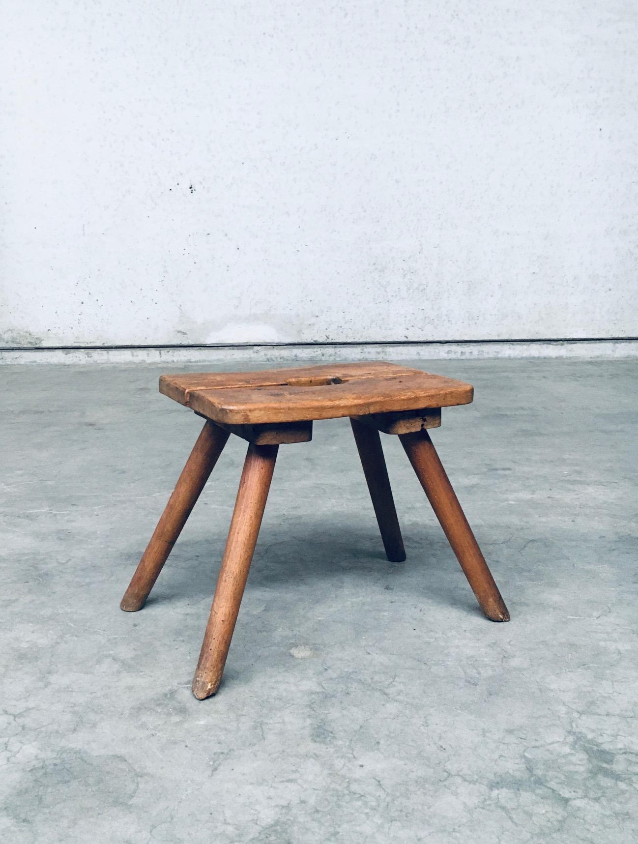 Original Craftsman Handmade Folk Art Milk Stool. Made in Belgium, late 1800's - early 1900's. Solid oak constructed stool with central handgrip. Simple in design, with 4 turned legs and a seat made of 2 solid planks with a carved handgrip for easy