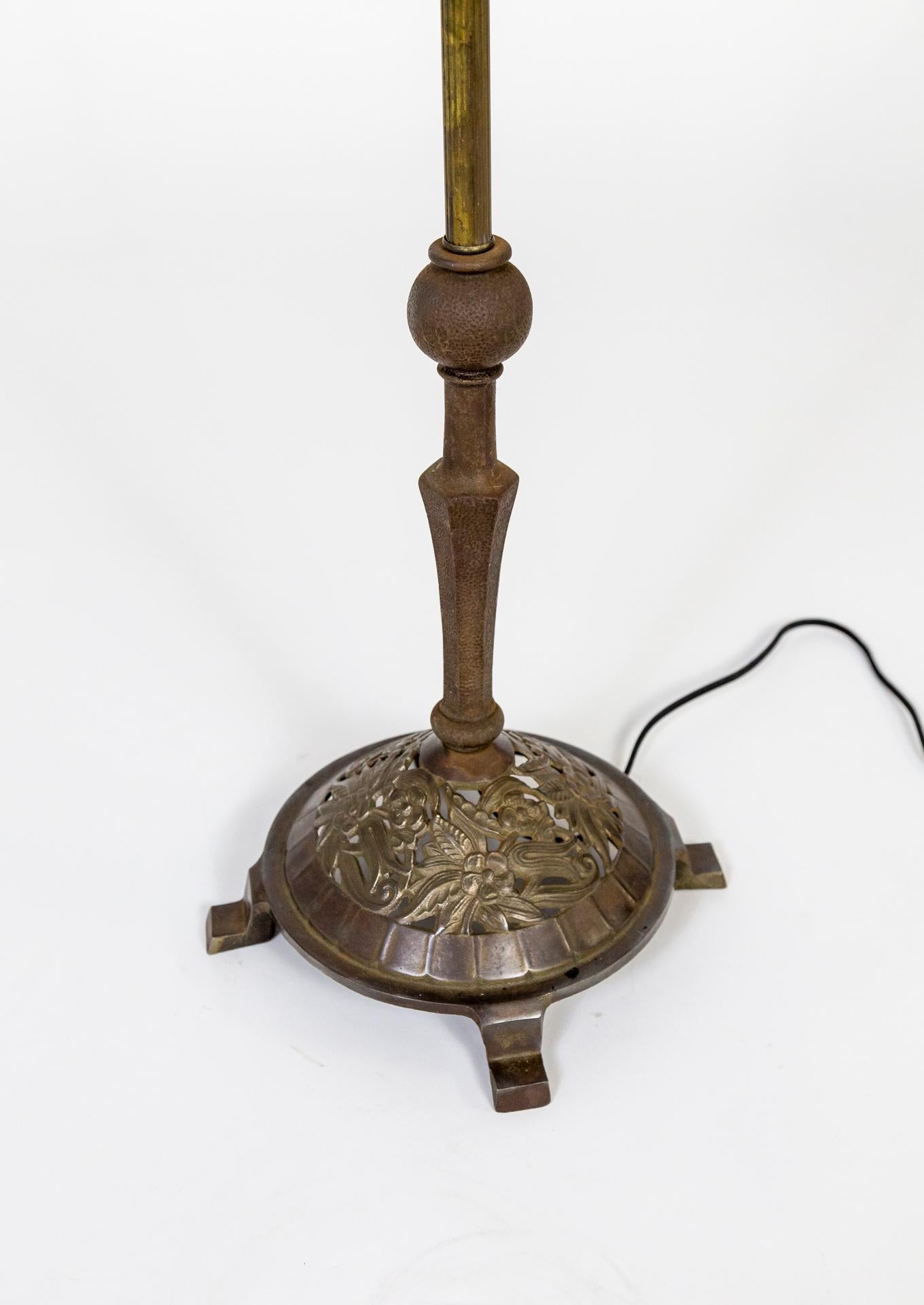 A heavy, brass and wrought iron harp floor lamp with a dome shaped base with beautifully cast flowers. In Art Deco, Craftsman style, with a molded, angular, frosted glass shade; adjustable neck and original switch on the socket. Early 20th century.