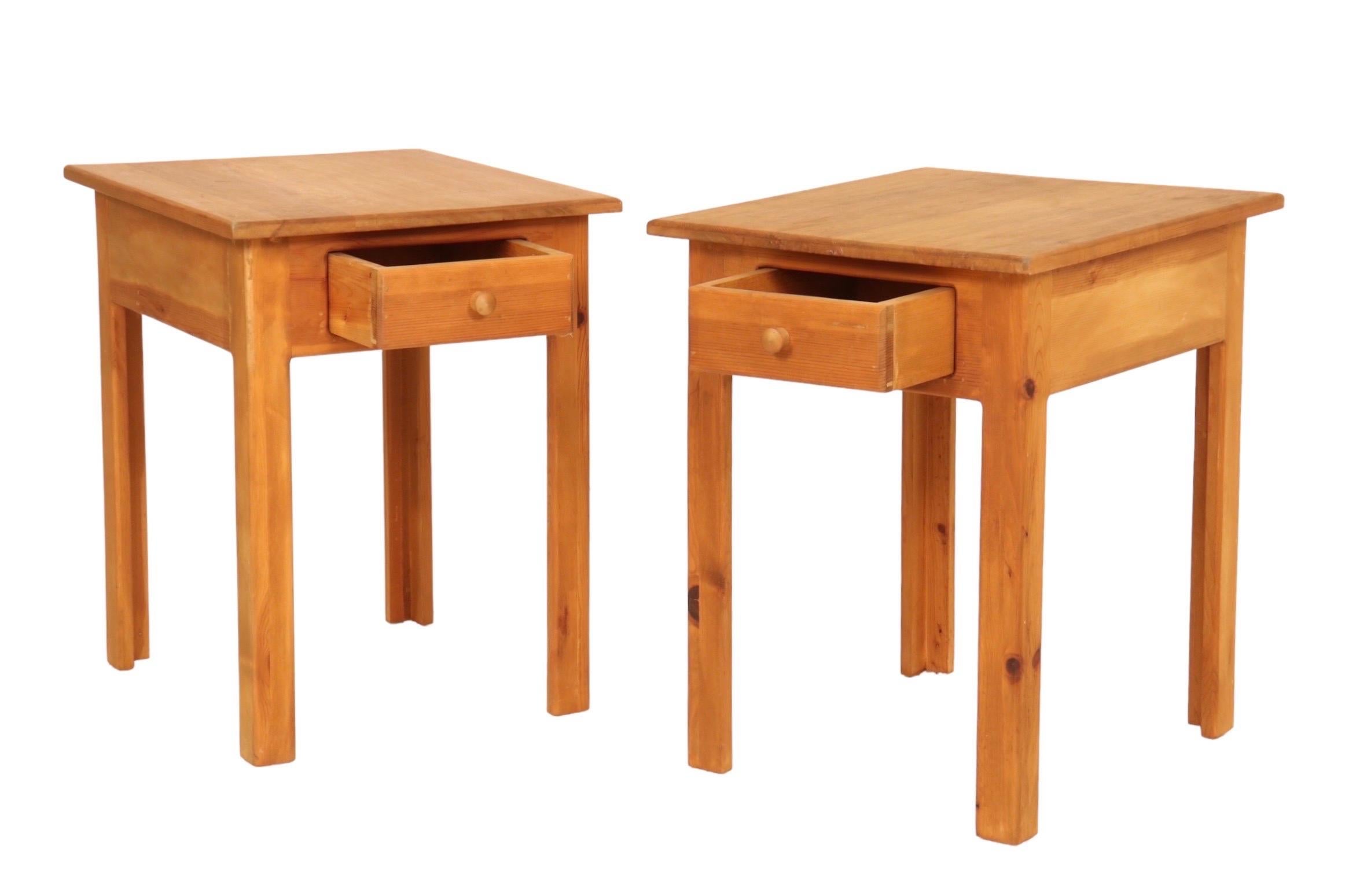 A pair of craftsman style side tables made of knotty pine. Each has a single drawer that opens with a mushroom shaped knob handle and stands on straight L-shaped legs. Dimensions per side table.