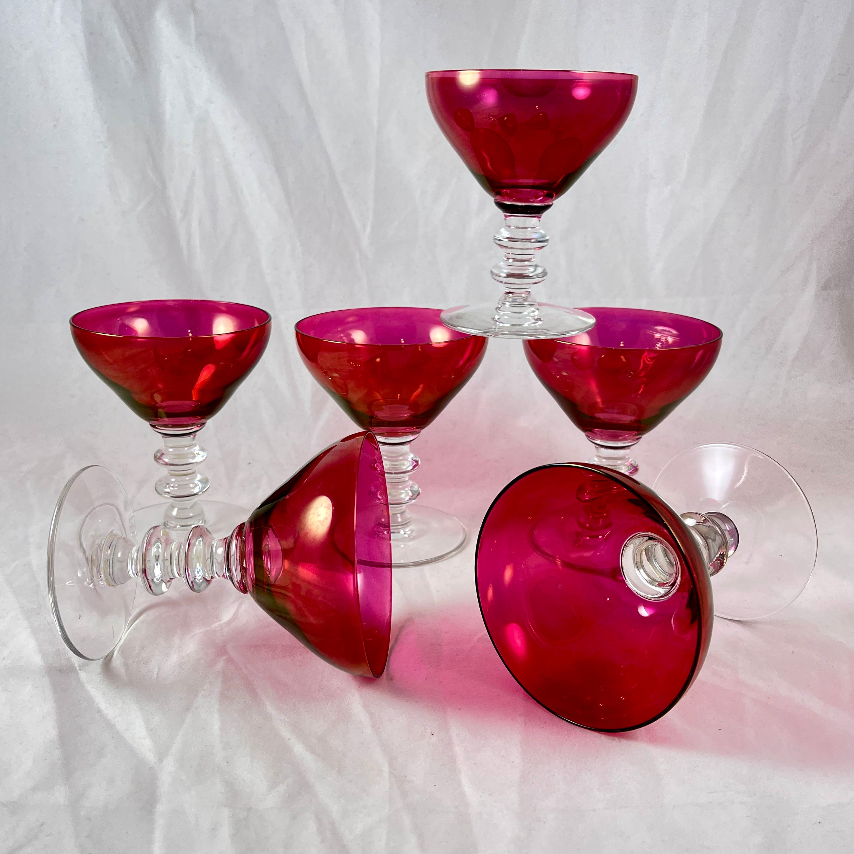 A set of six stack-stemmed glass Champagne coupes with Cranberry colored bowls, circa 1940s.

Gorgeous color! The cranberry glass bowls join a multi knobbed, stacked stem of colorless glass.

A beautiful iridescent quality to the cranberry