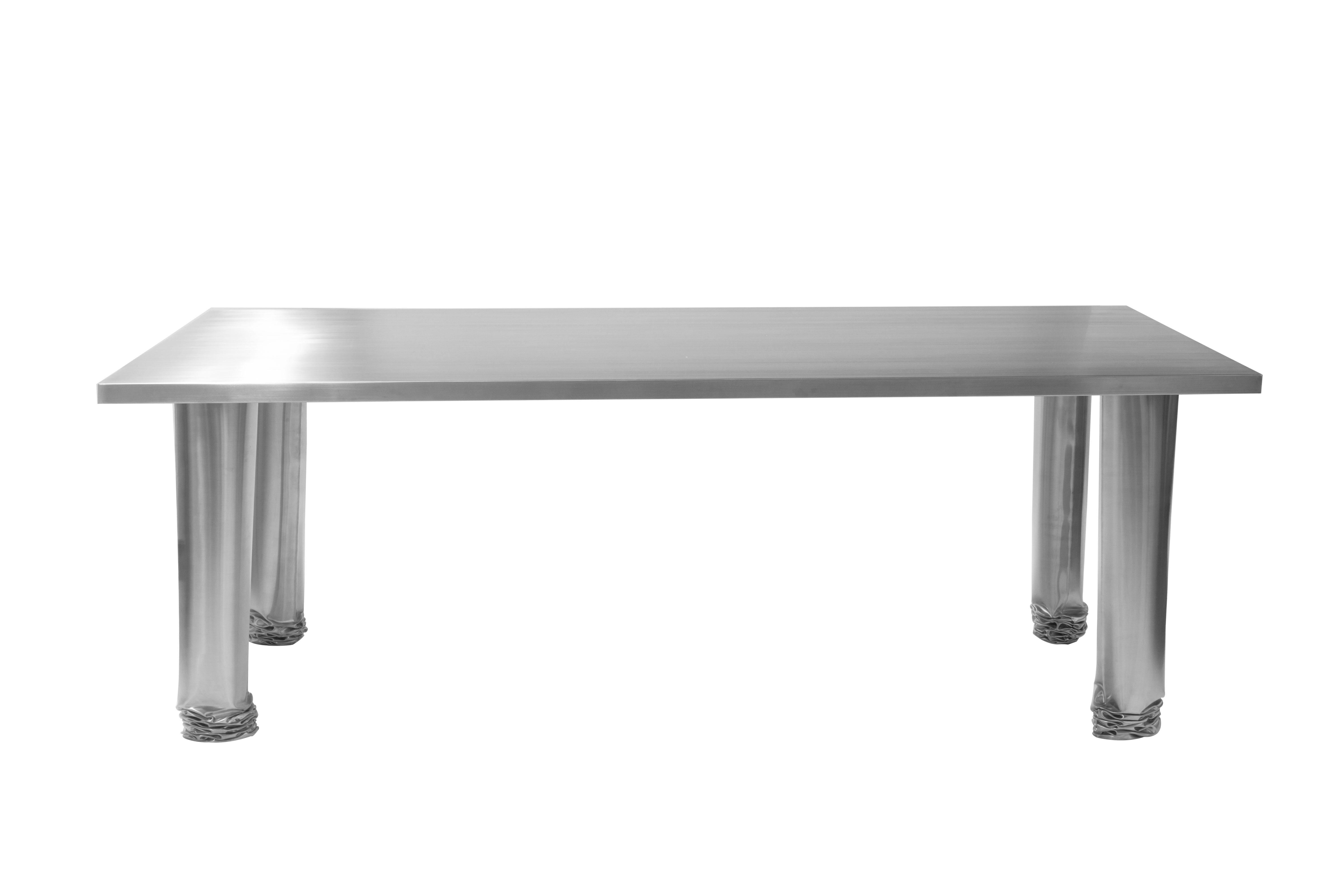 Crash table by Zieta
Dimensions: D 100 x W 220 x H 75 cm
Materials: Satin stainless steel.

Crash Table is the materialization of a “controlled loss of control”, when what appears to be accidental is in fact the result of a carefully planned