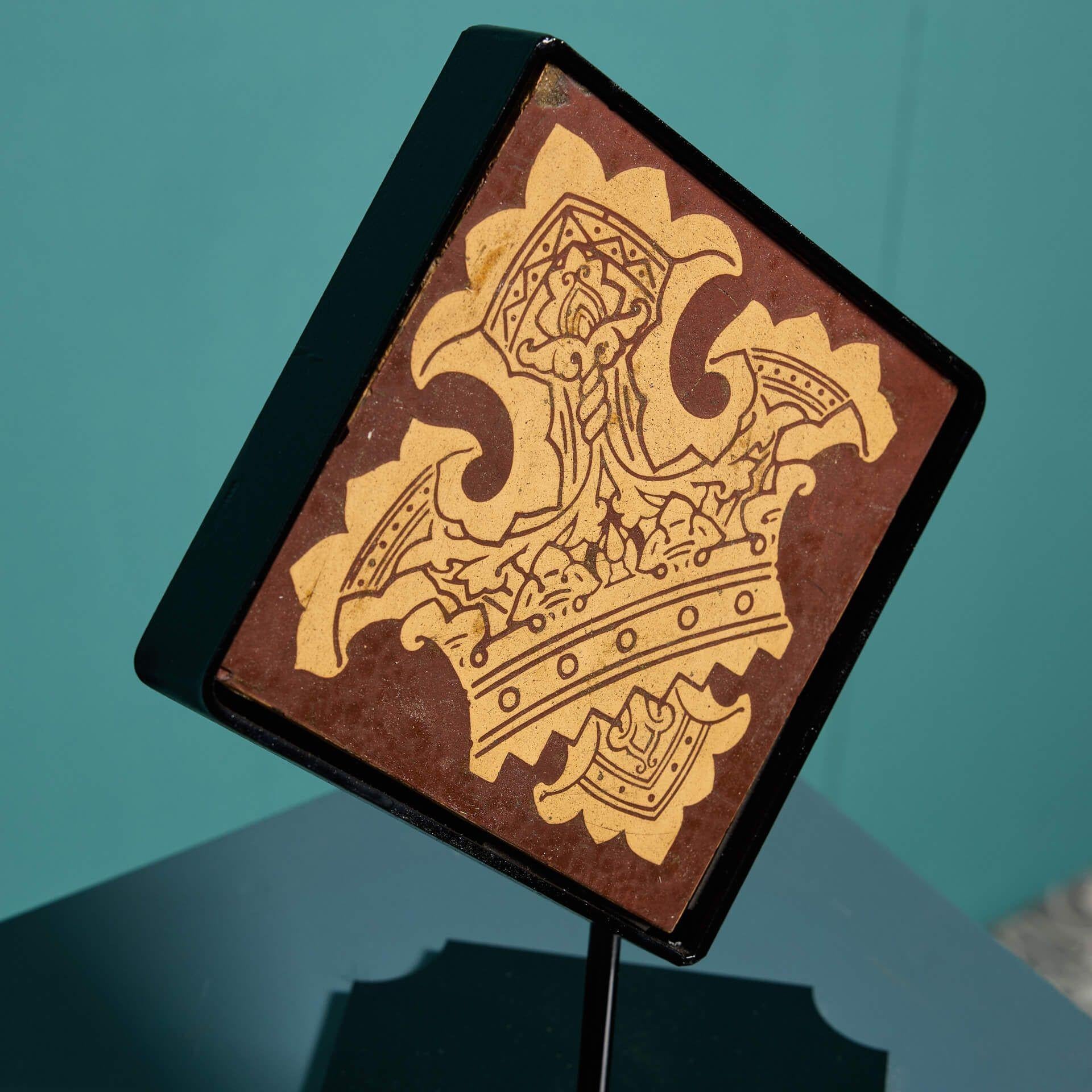 A late 19th century encaustic floor tile by Craven Dunhill and Co (stamped) depicting a neo-medieval crown in deep red and buff tones. This 6-inch tile includes a bespoke steel stand as pictured, making it a stunning decorative interior piece for