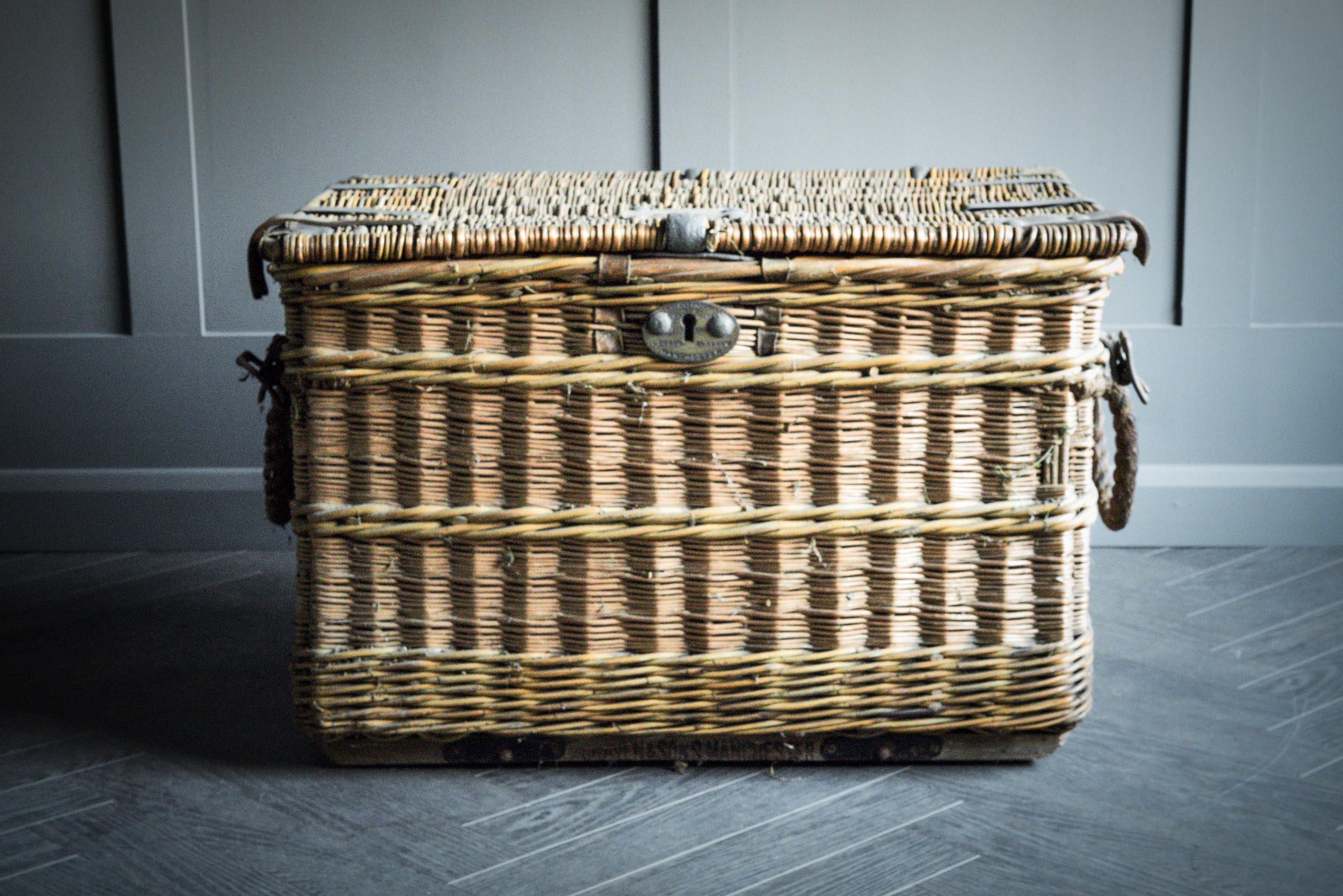 Cravens Laundry basket made from wicker with thick rope handles on either end, finished with leather straps and clasp for fastening.