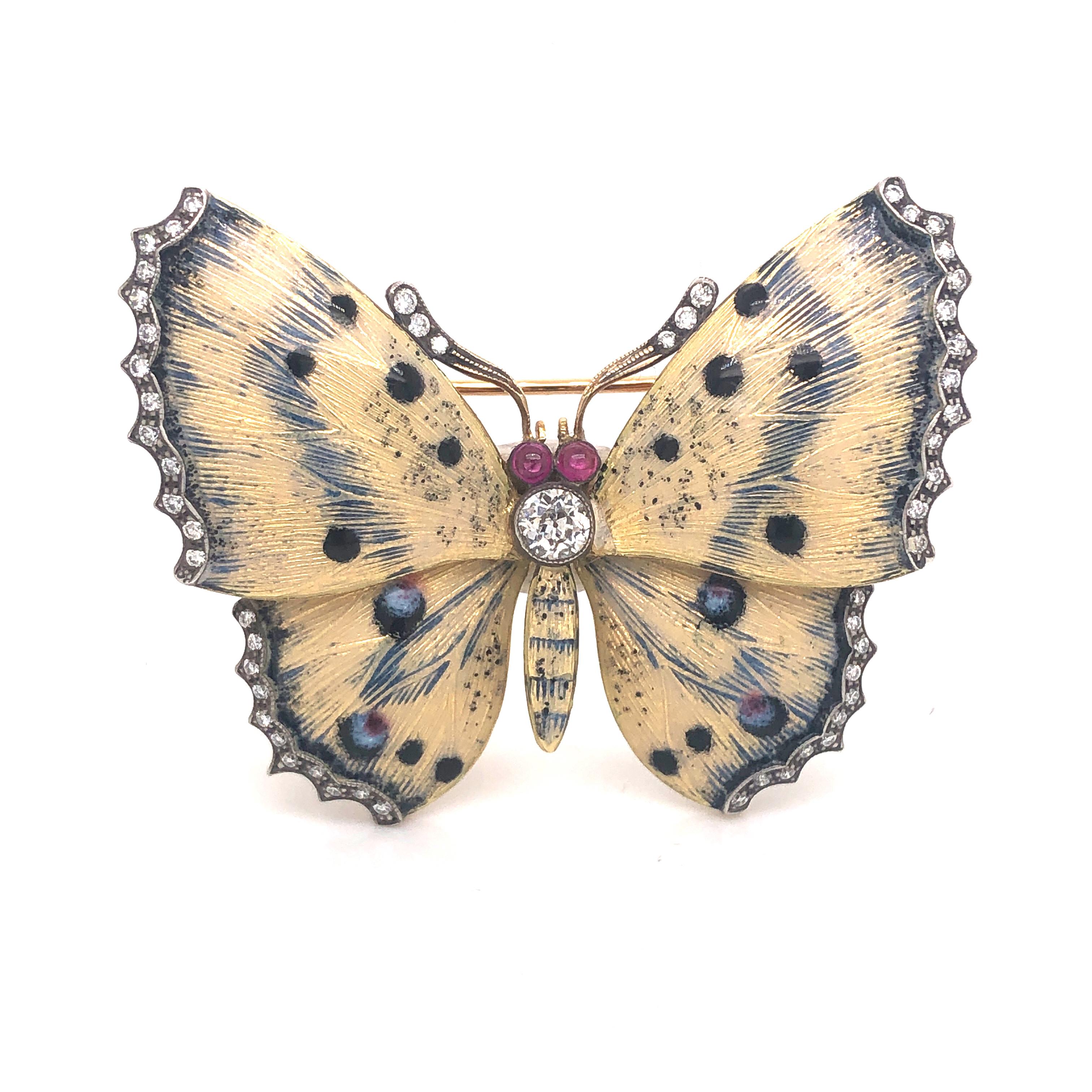 A cream and dark blue guilloche enamel butterfly brooch, set with a single brilliant-cut diamond to the thorax, and further diamonds set to the wing edges, weighing approximately 0.75ct in total, with two cabochon-cut rubies for the eyes, all