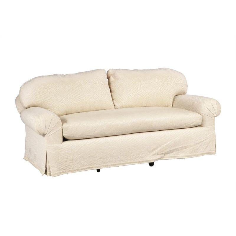 A cream Brunschwig & Fils fabric sofa with rolled arms, single bench seat, two cushion back and tailored skirt.  