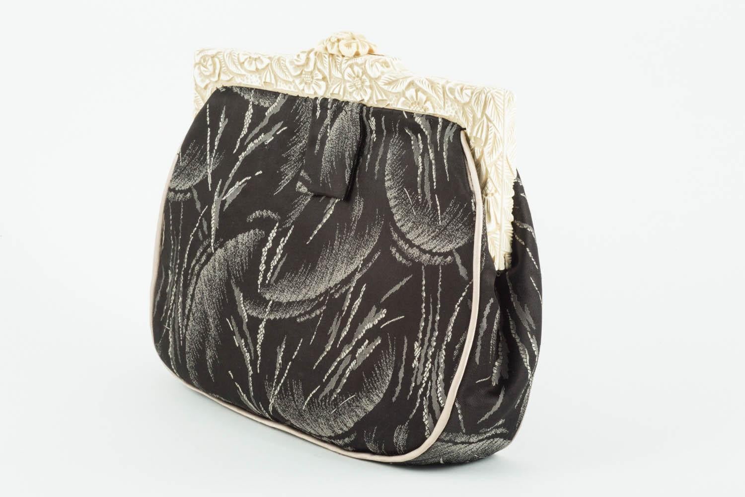 These is a delightful clutch bag, made from a beautiful Art Deco silk fabric, and piped in grey silk. The frame is of an off white/cream carved Bakelite with motifs of leaves and flowers, and the interior is of sage silk, with a lemon and aquamarine