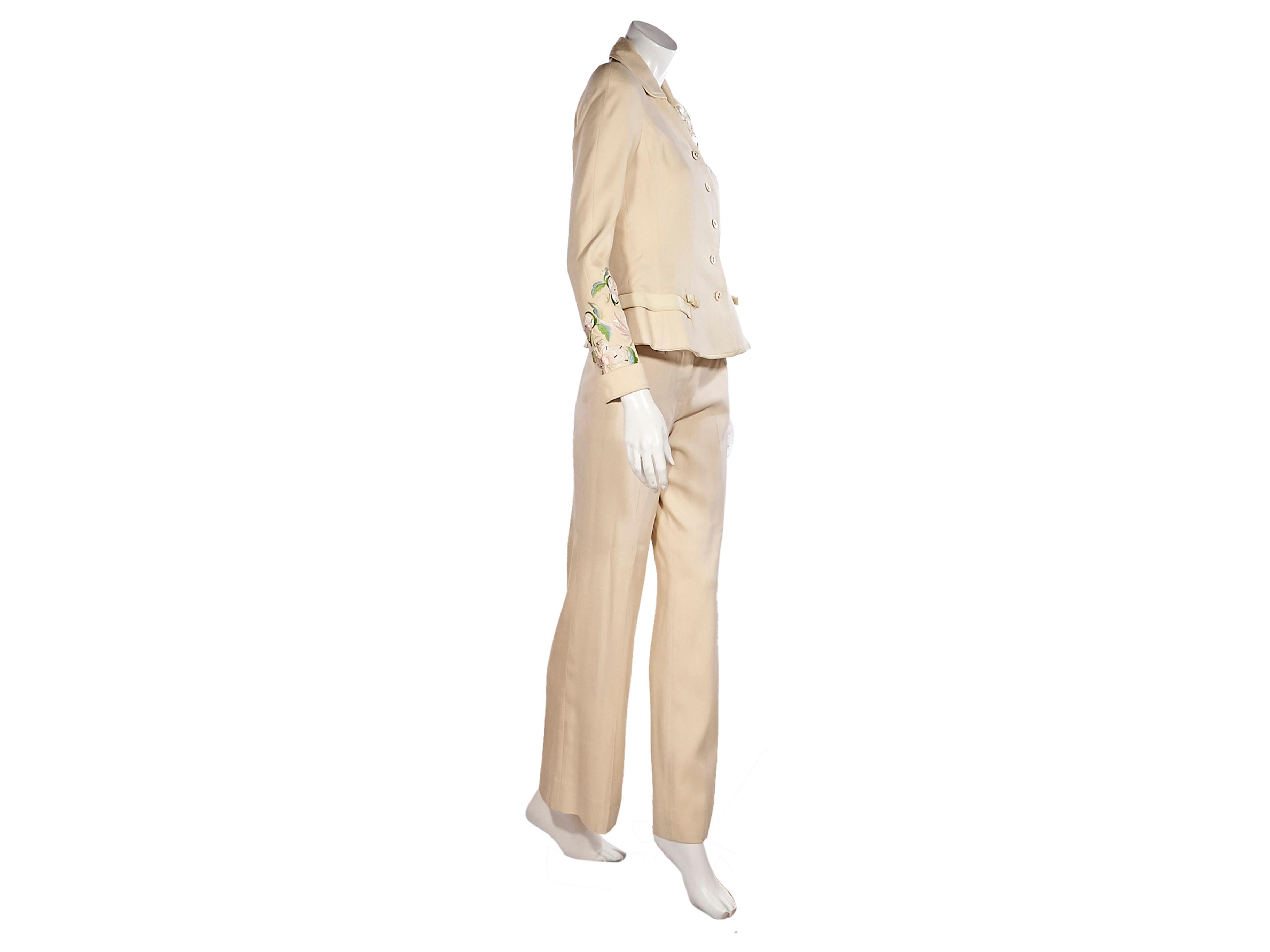 Product details:  Cream silk floral-embroidered suit by Christian Dior.  Trimmed with leather.  Spread collar.  Long sleeves.  Button-front closure.  Back hem slits.  Matching dress pants.  Banded waist with belt loops.  Concealed hook and zip