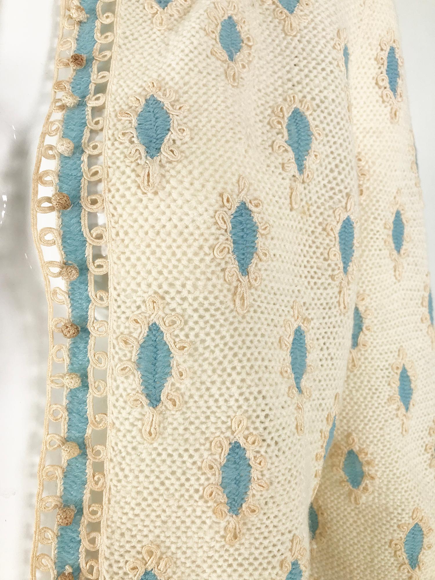 Cream crochet & cream cord work applique cardigan sweater from the 1960s, handmade. Cream knit sweater is interspersed with ovals of blue crochet each is surrounded with applique cord work. The sweater has a Peter Pan collar that is trimmed with