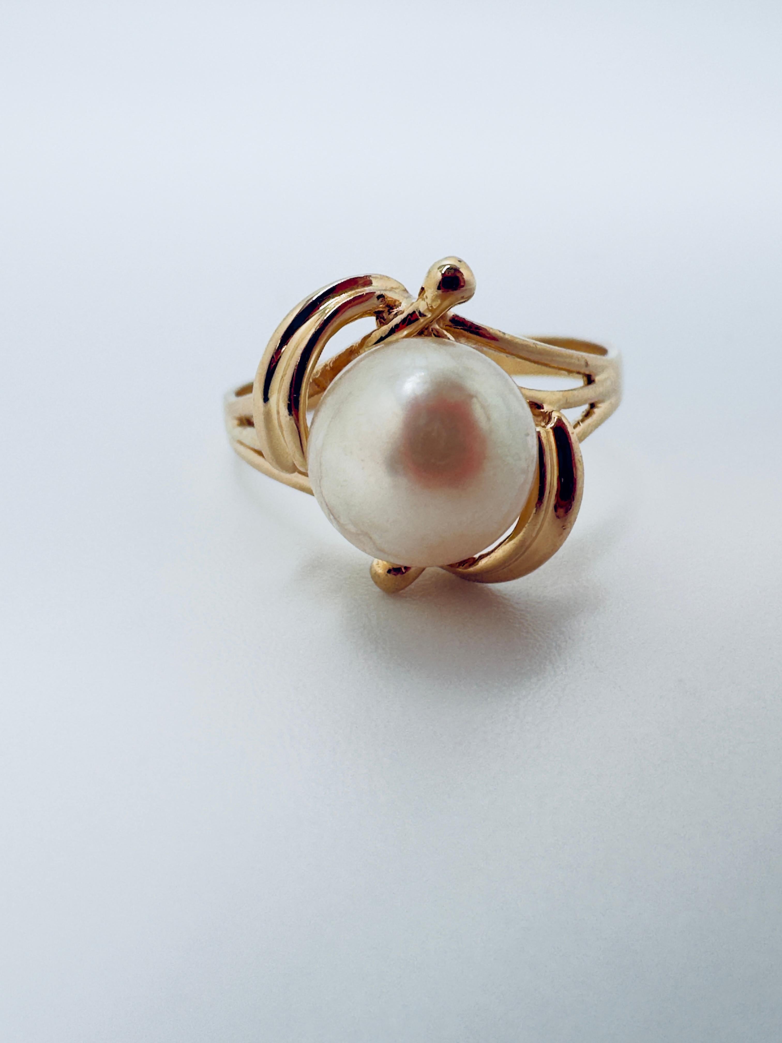 Cette élégante bague en or jaune 14 carats est ornée d'une perle d'eau douce ronde de 7,00 mm de diamètre d'une douce couleur crème. La perle est cultivée et conçue avec un sertissage demi-percé, ce qui lui permet de reposer en toute sécurité sur le