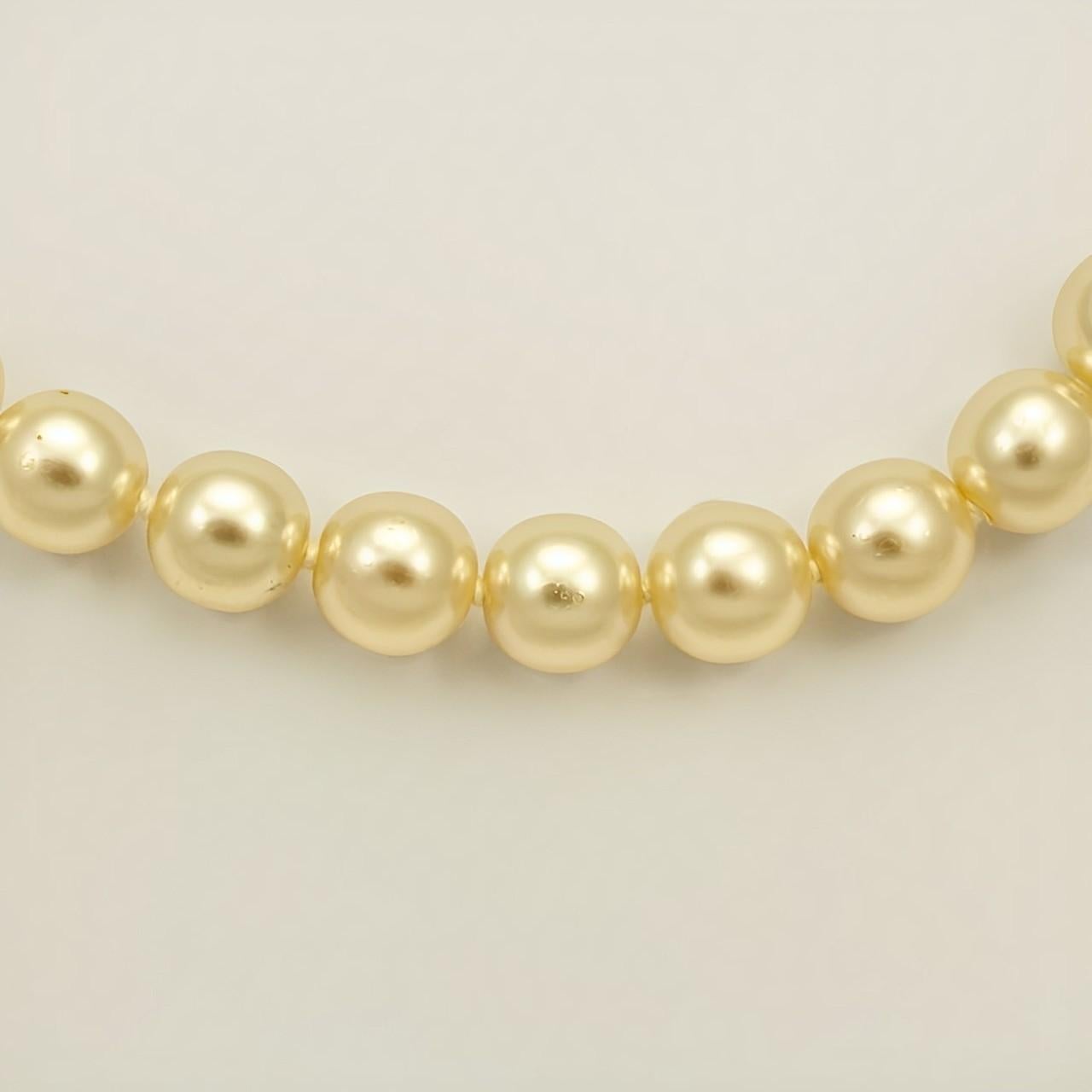 Wunderschöne cremefarbene Glasperlenkette mit einem runden, vergoldeten, geriffelten Verschluss, der mit drei Perlen besetzt ist. Die glänzenden Perlen werden zwischen den einzelnen Perlen geknotet. Messlänge 43,5 cm / 17,1 Zoll. Die Perlen sind 9