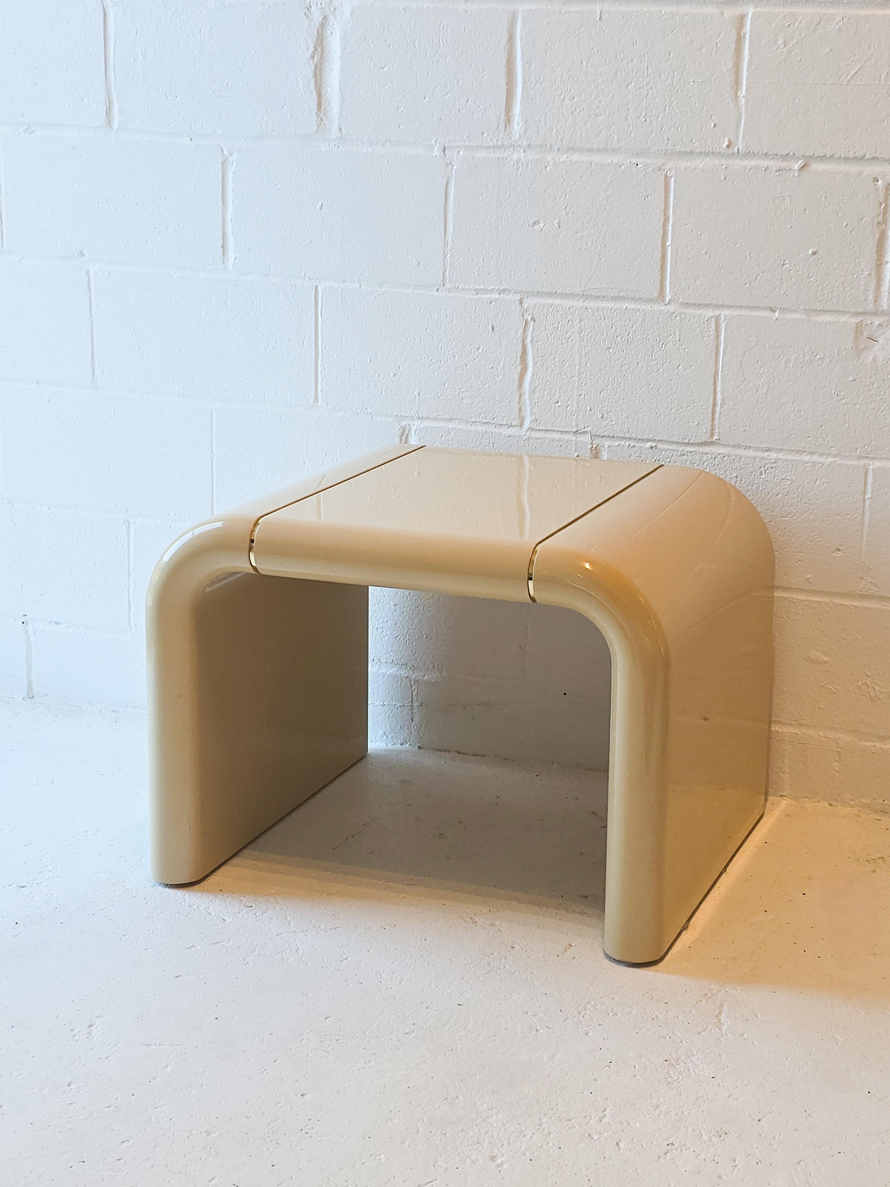 Gorgeous lacquered cream side table with with a gold inlays. In the style of Karl Springer. The waterfall shape is one piece with a unique gold inlay in the middle of the top of table. In overall good/fair condition with some signs of wear,