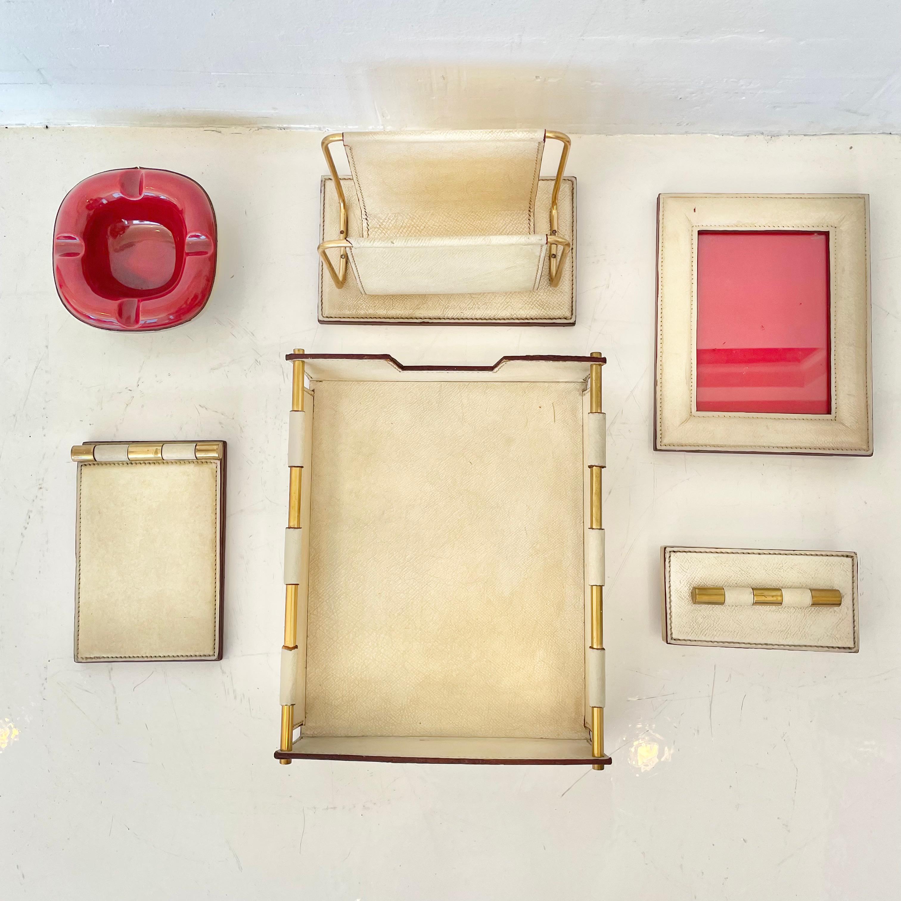 Fantastic 6-piece French leather desk set by Longchamp. All pieces wrapped in cream leather with incredible patina and character and accented with solid brass. Desk set includes: desk pad, mail holder, paper tray, picture frame, red ceramic ashtray