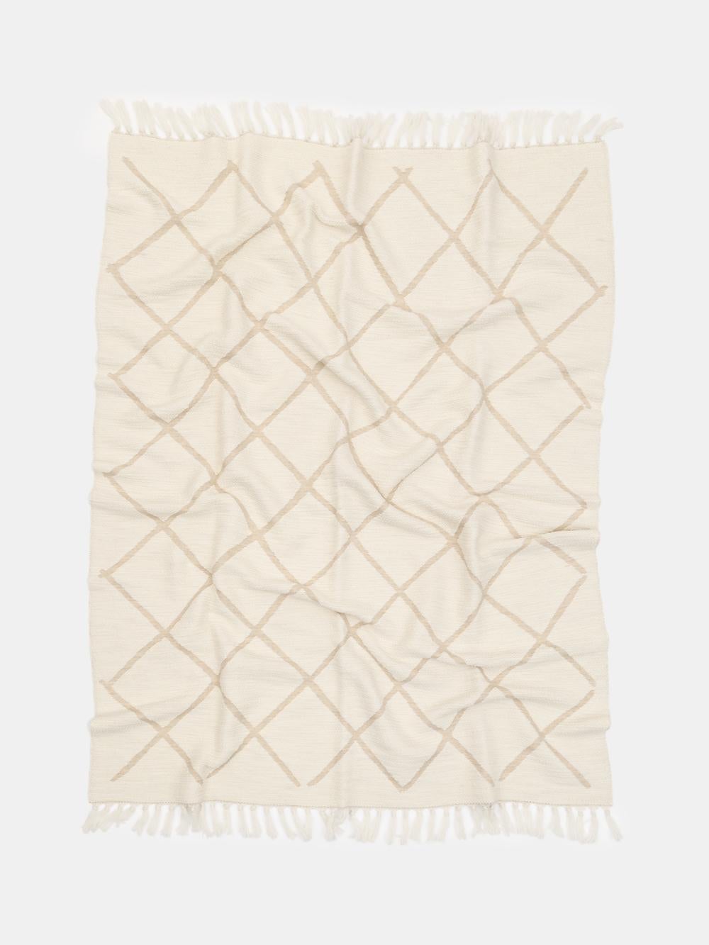 Cet élégant jeté en laine mérinos, fabriqué à Como, en Italie, allie une chaleur naturelle à une douceur et une légèreté exceptionnelles. Le motif jacquard à losanges raffiné présente un magnifique design réversible - un côté en blanc doux avec un