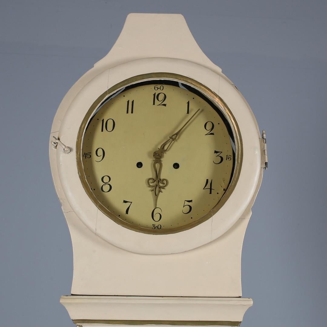 Antique Swedish country Mora clock from early 1800s in probable original cream paint finish with a great delicate shape body and a good face with lots of detail and nicely detailed hood in good condition. 

It has the Classic extended belly of a