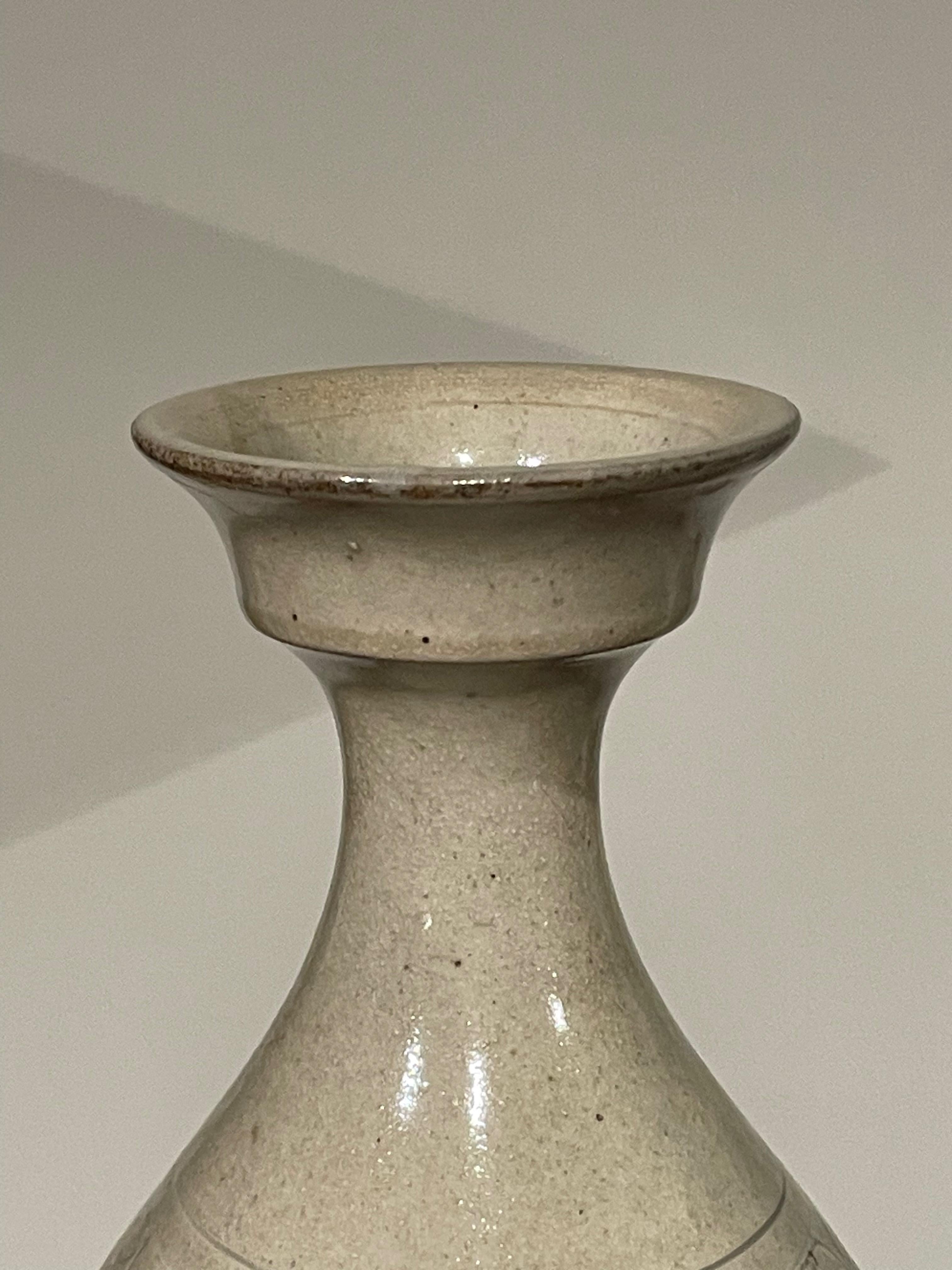 Vase contemporain chinois à motif crème.
Dessus en forme de coupe.
Bandes horizontales de motifs décoratifs circulaires.
ARRIVÉE EN AOÛT

 
