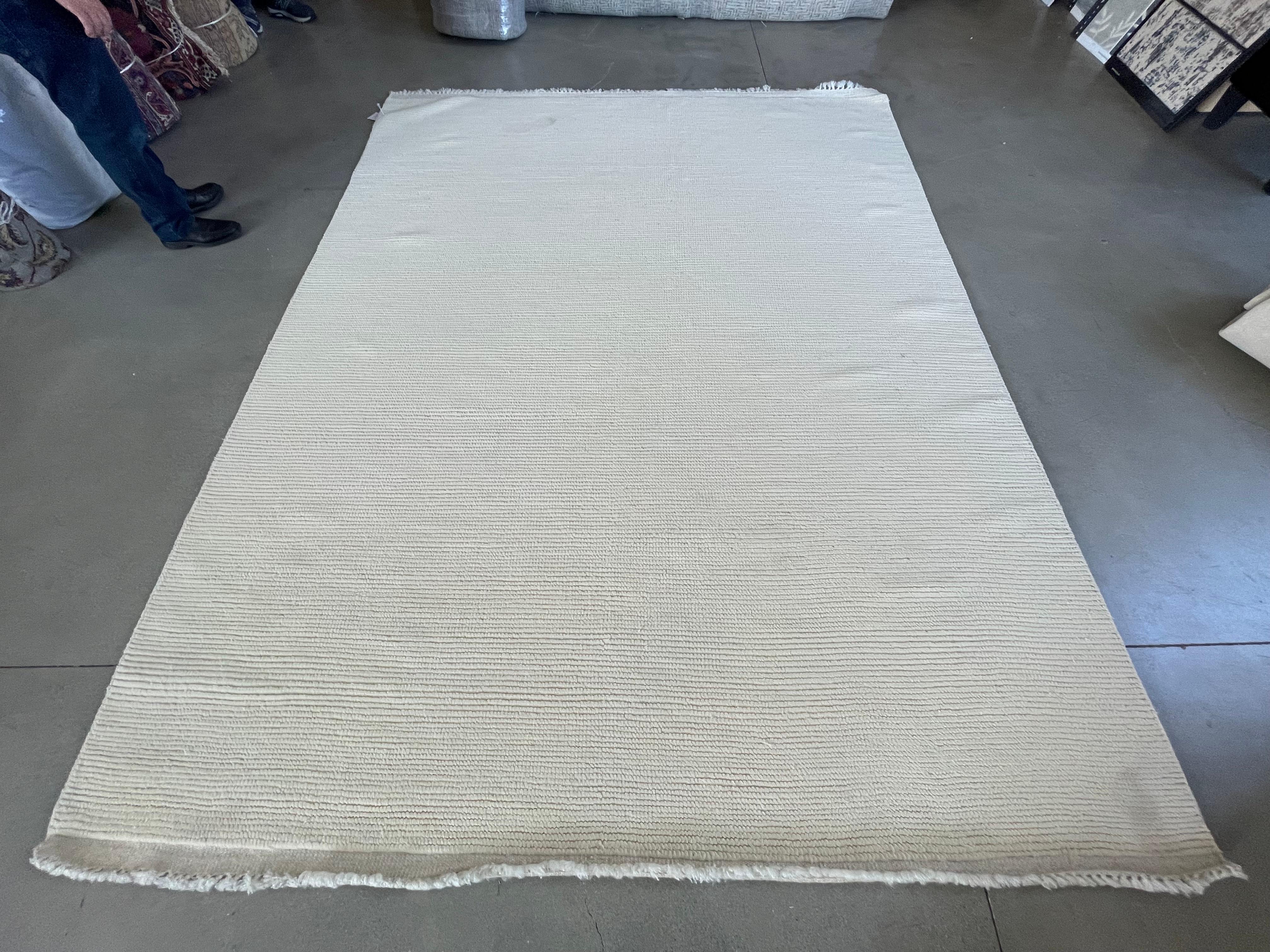Dieser 8x10 große, cremefarbene, gerippte Teppich mit marokkanischem Design stammt aus unserer neuesten Kollektion marokkanischer Designs und wurde in Indien handgefertigt und handgeknüpft. Es hat eine Baumwollbasis und ist aus reinen Wollgarnen