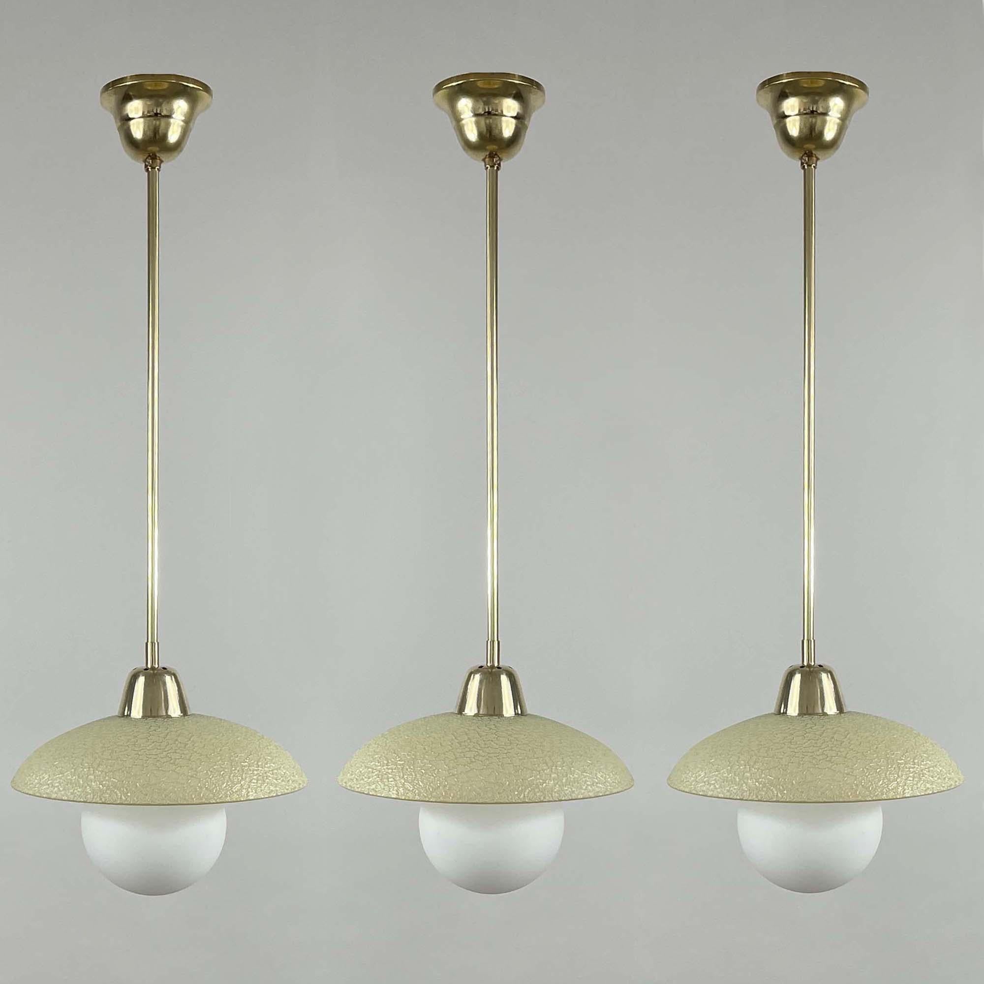 This elegant minimalist pendant was designed and manufactured in Sweden in the 1940s to 1950s. 

The light features a round cream colored crackle glass textured lampshade and brass hardware. It requires one E27 bulb and has been rewired for use in