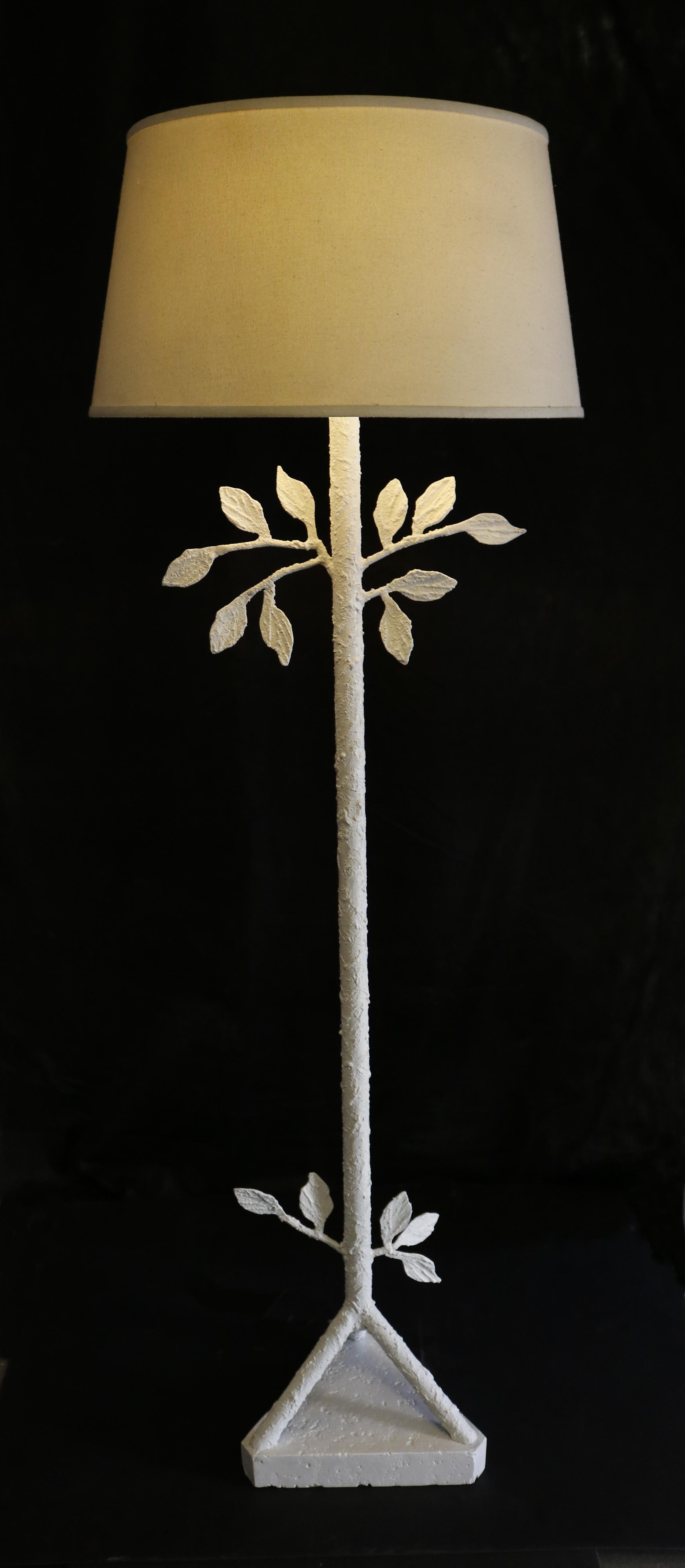 A unique floor lamp painted in white textured stucco along the stem, down to its' unique triangular base.
 There is also well-crafted leaf sculpture detailing on the stand reminding the work of Alberto Giacometti.