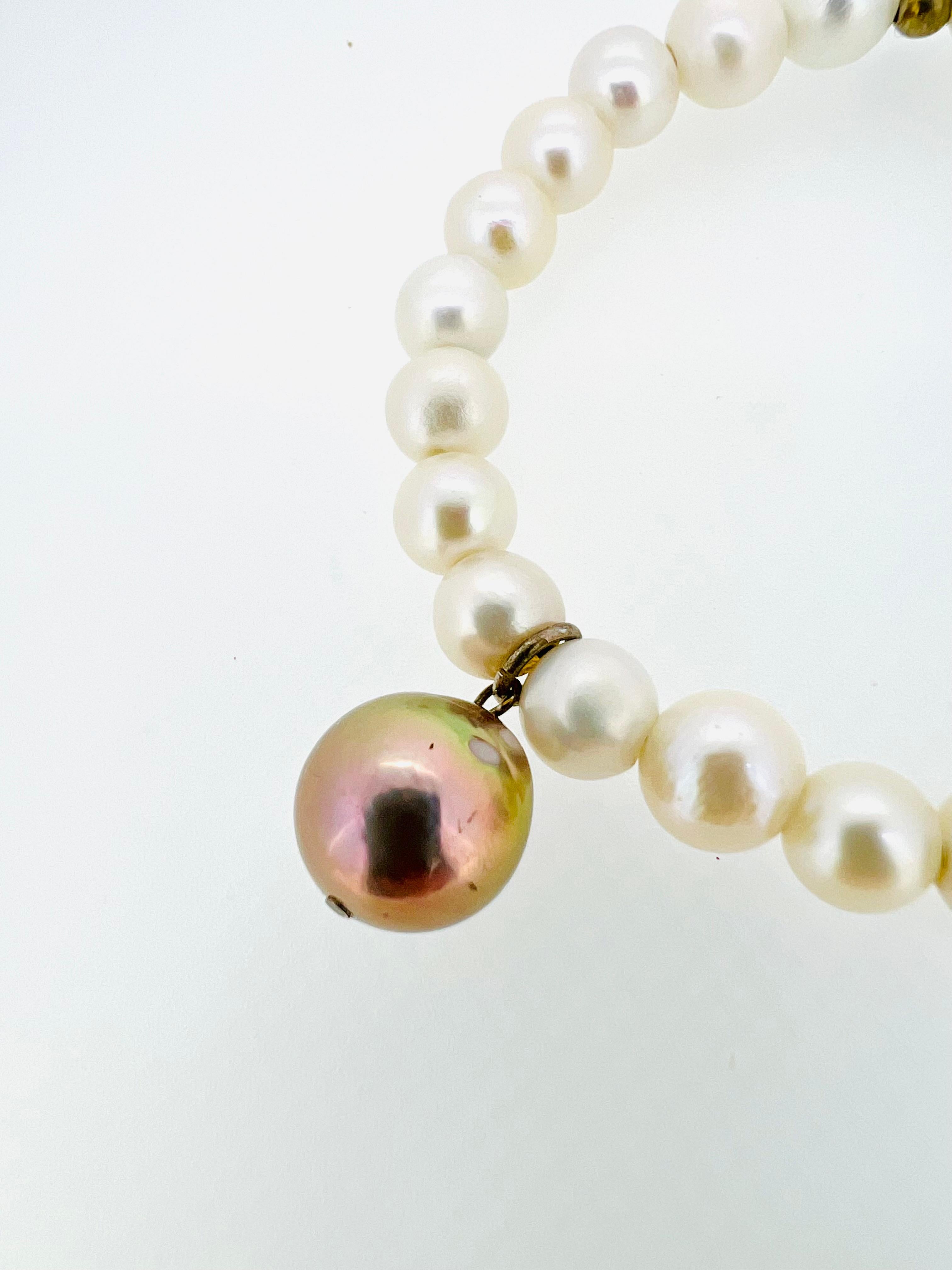 A bracelet made from creamy white freshwater pearls, featuring a stunning baroque freshwater pearl that elegantly dangles. Strung on a black cotton-coated elastic cord, this bracelet easily slides over the wrist, making it the perfect accessory to
