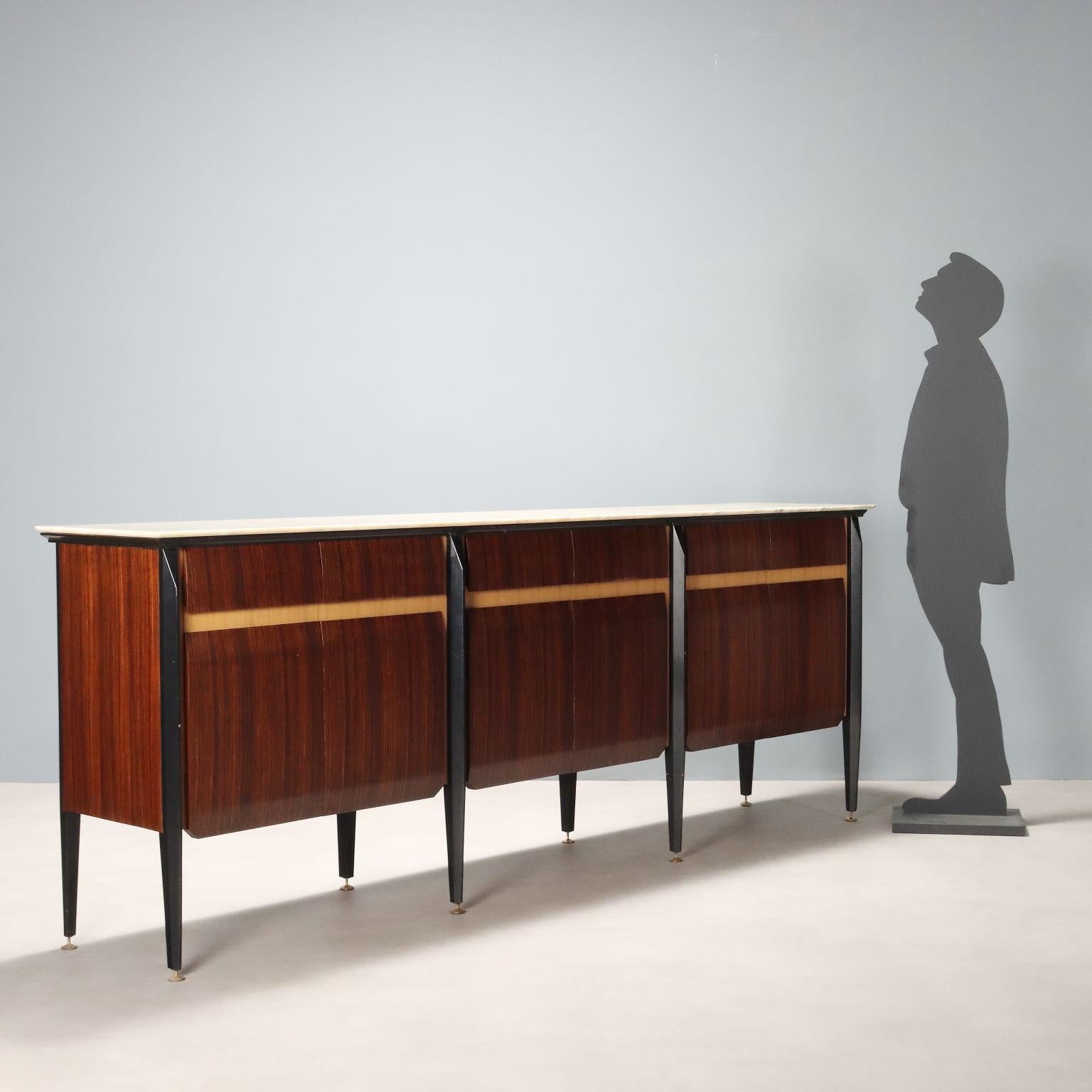Elegant vintage sideboard with exotic wood veneer and laminate inserts, features white marble top, hinged doors concealing shelves and drawers, eight stained wood legs with brass feet.
