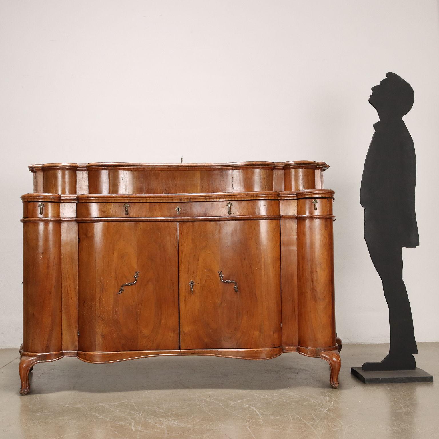 A Ferrara-made Baroque credenza supported by en cabriole feet, it has a moved front in which there are pairs of doors and drawers in the fascia: a large-sized central one and two smaller side ones; the sides are also moved and have one door each. A