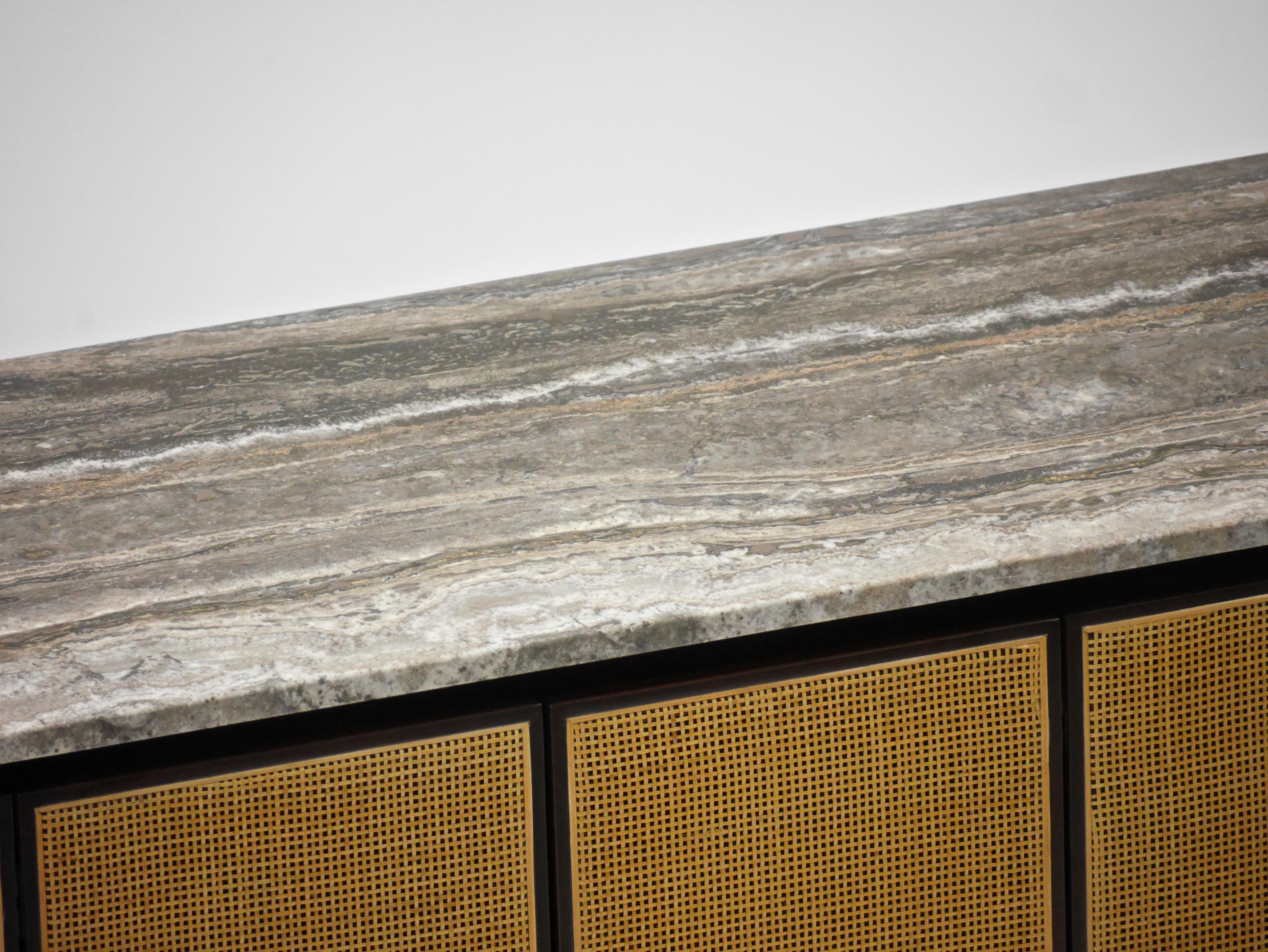 Credenza by Paul McCobb for Calvin. Six cane front folding doors, a custom Persian silver travertine top, brass legs, two storage compartments each with a shelf.

Refinished, top has been honed filled and sealed.