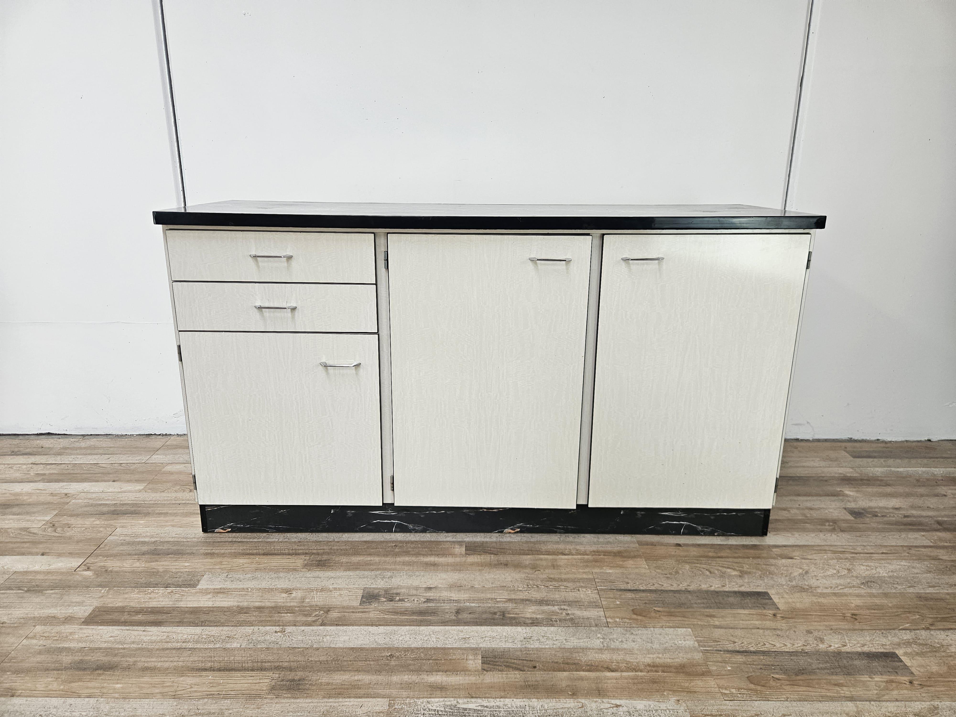 Vivace credenza da cucina in formica bianca e crema, con un bellissimo effetto marmorizzato sul top principale e lungo il bordo alla base.

Credenza dallo stile moderno, originale degli anni '70 italiani.

Si presenta con un doppio cassetto sul lato