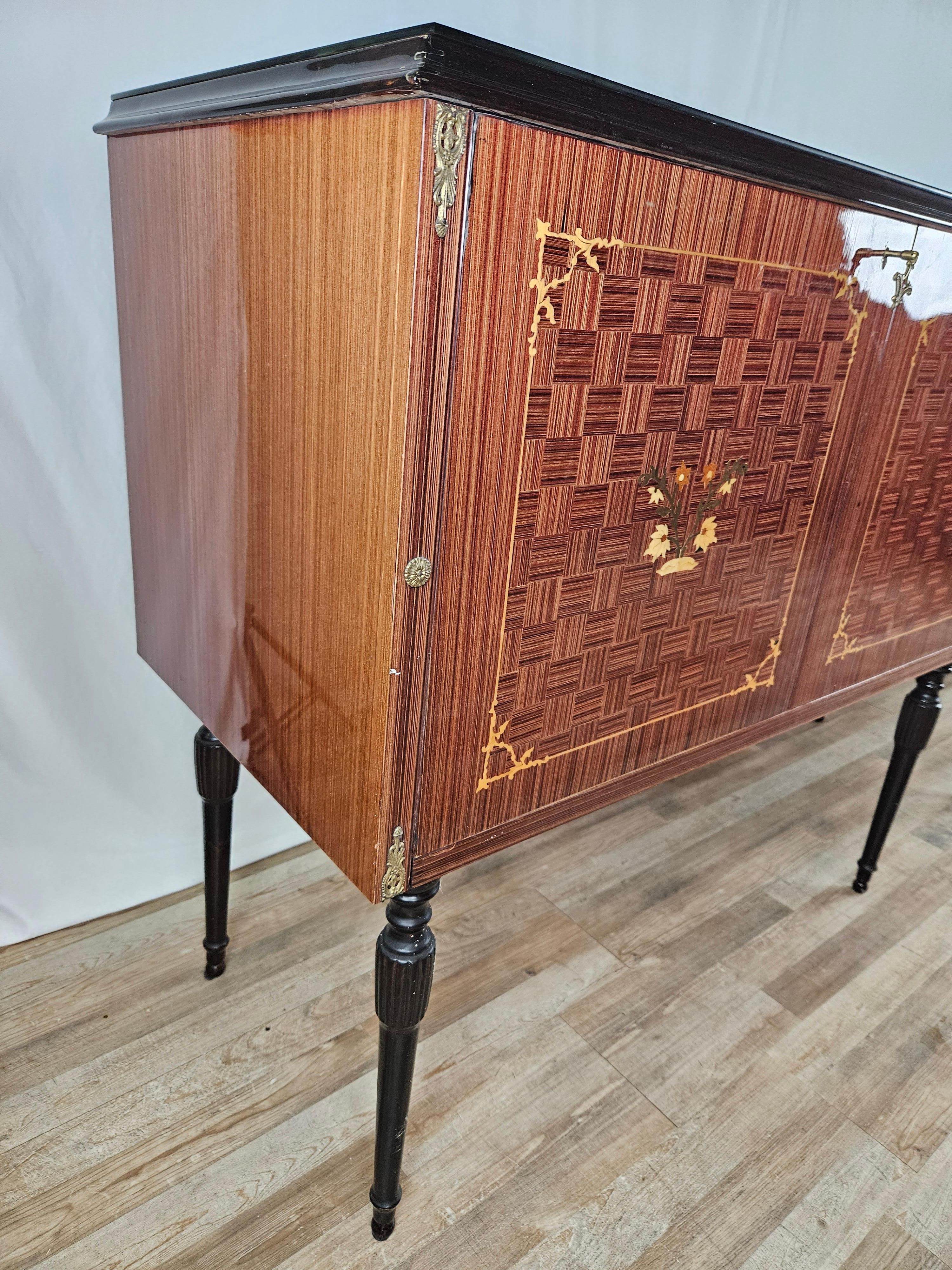 Mid-20th century Italian-made wooden living room sideboard, fine and linear frame with brass decorations and ebonized pin legs.

The glass is finely decorated with a variety of shades, linear measurements and well-defined contours make this piece of
