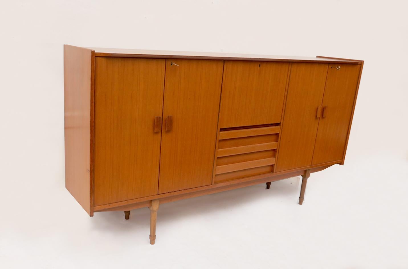 Nordic-style highboard sideboard, dating from the 1960s of the 20th century.
The cabinet is made of teak veneer wood and has two compartments with double shelves, closed by four doors that open in a compass shape. In the central part, at the bottom,