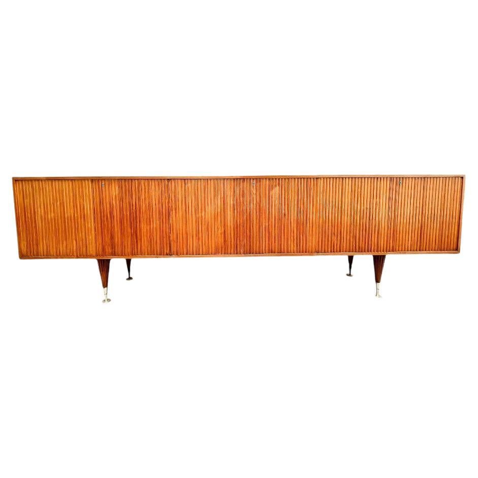 This one of a kind reeded credenza was designed by Giuseppe Scapinelli in the 1950s. It is made with Caviuna wood and features four tapered legs, six doors, and eight shelves. The wood has a beautiful and rich tone with stunning natural wood grain.