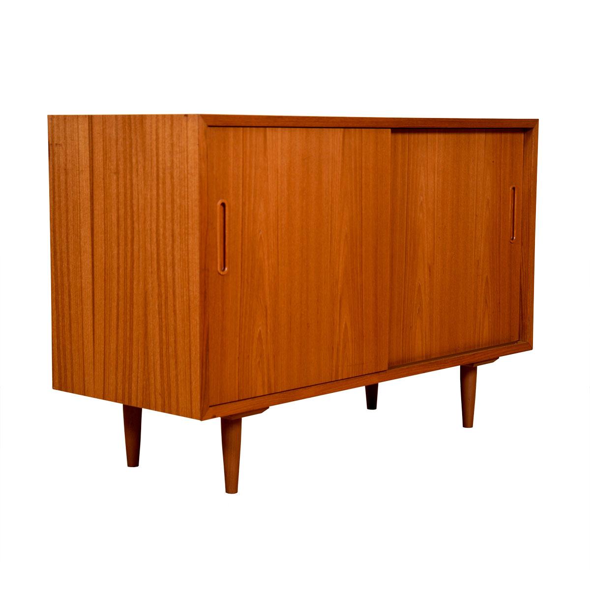This compact Danish Modern credenza / sideboard with adjustable shelves and one felt-lined drawer is the perfect candidate to house your media components. The handles are vertically-carved ovals with a small frame around. The piece has two